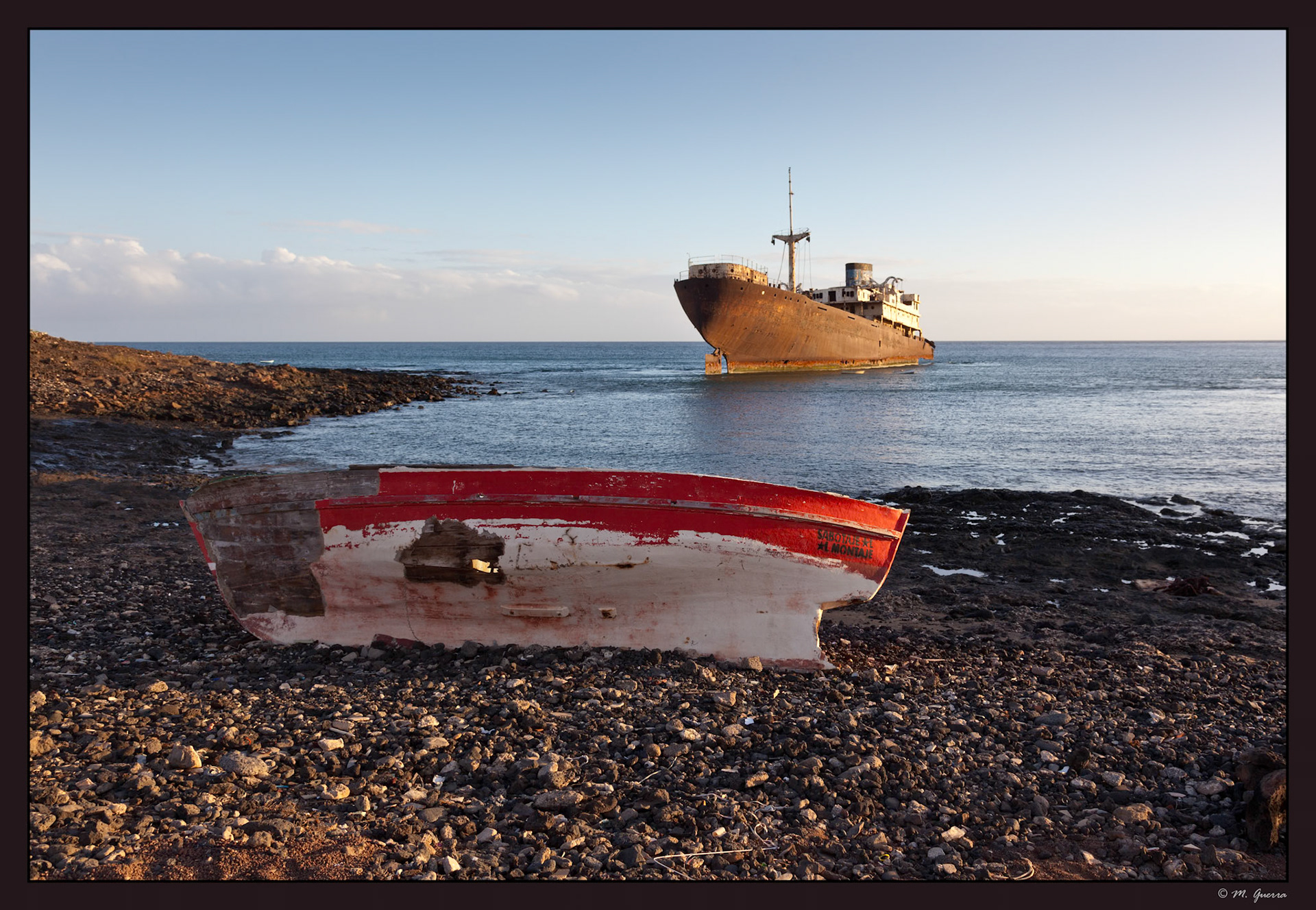 El pecio de un barco medio hundido en Costa Teguise en Lanzarote con una barca destruida en primer plano. Ampliar. 100ASA