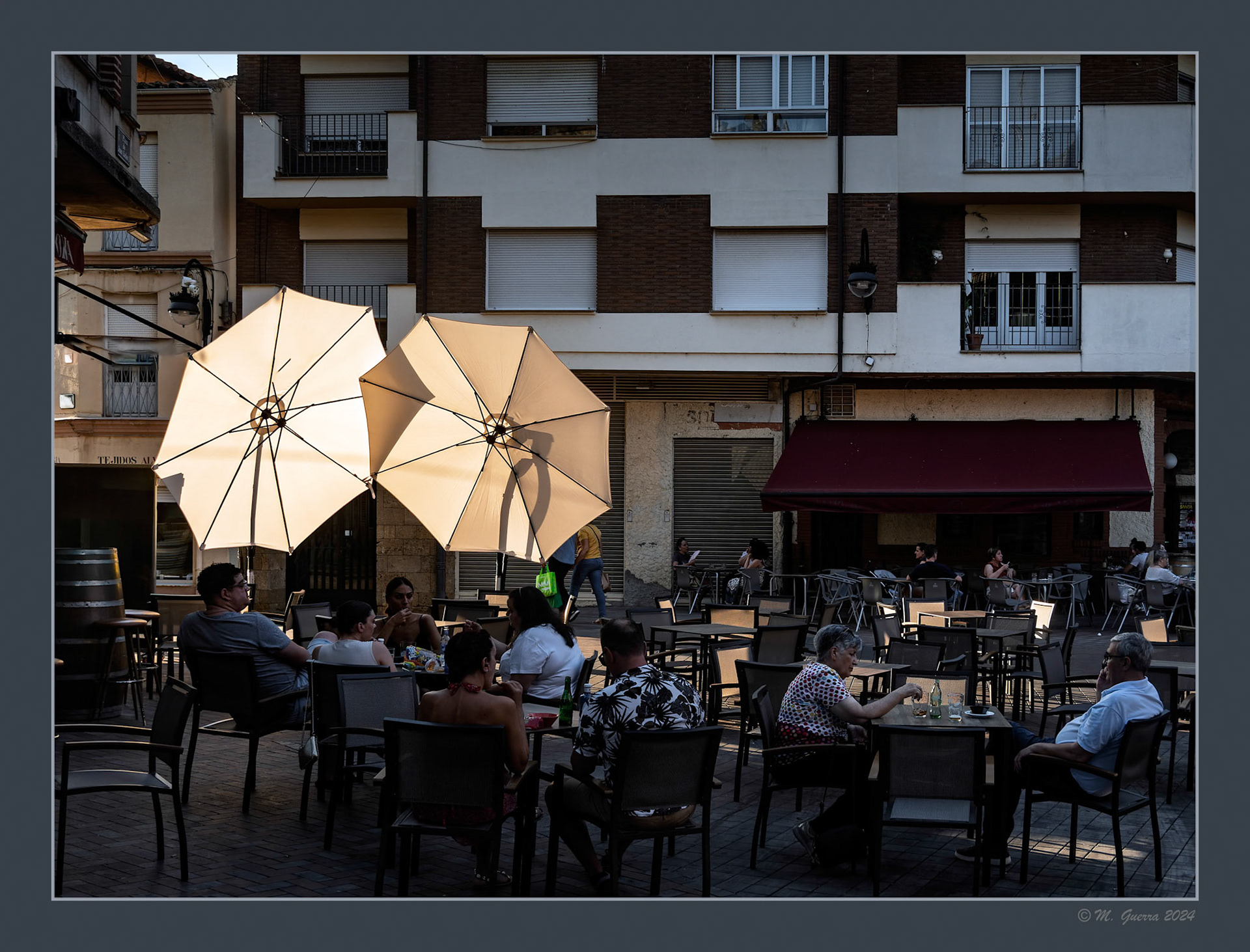 Dos sombrillas en una terraza de Benavente iluminadas por el sol al atardecer