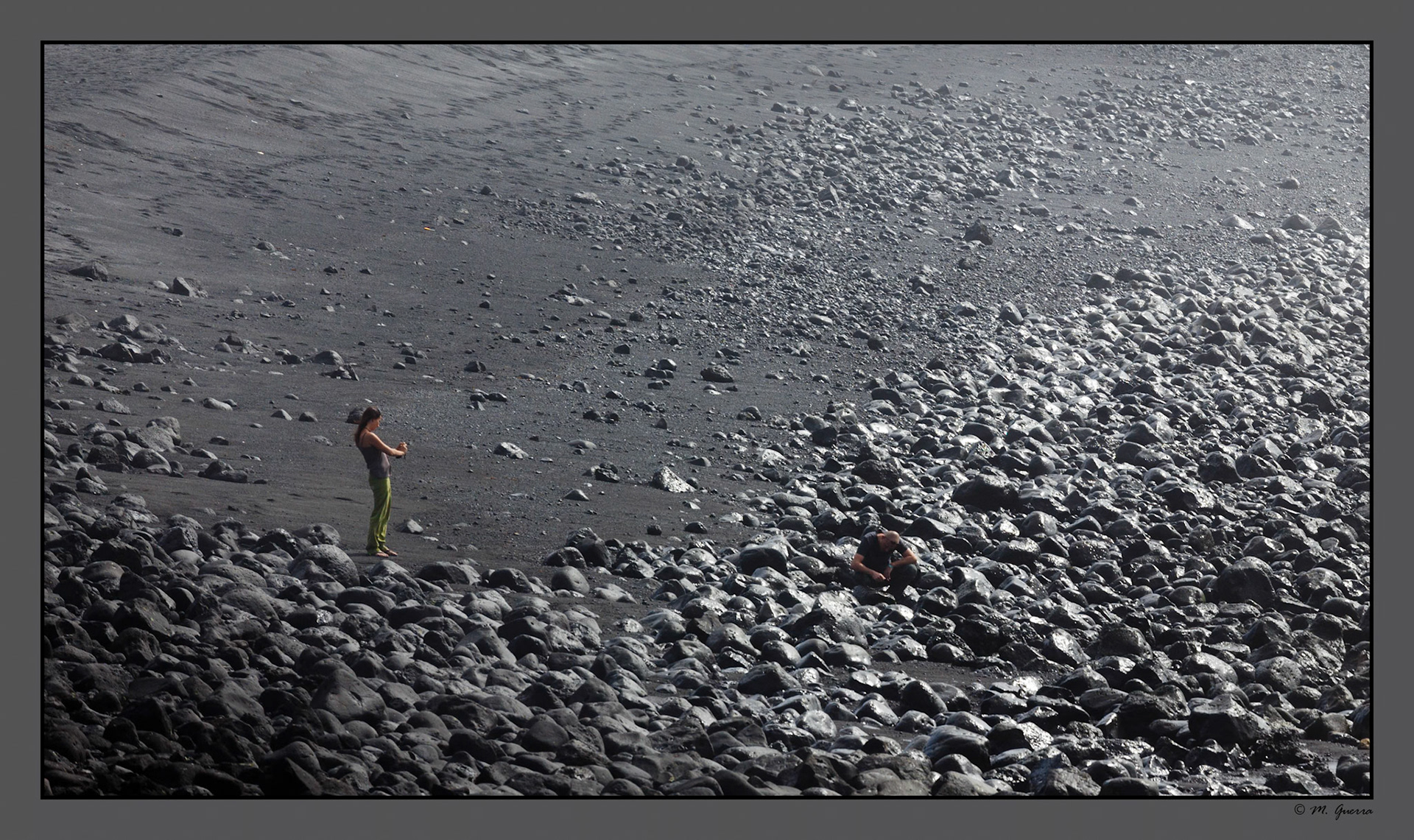 Una chica y un chico sentado en una playa rocosa en La costa entre Los Hervideros y las Salinas en Lanzarote. Ampliar. 100ASA