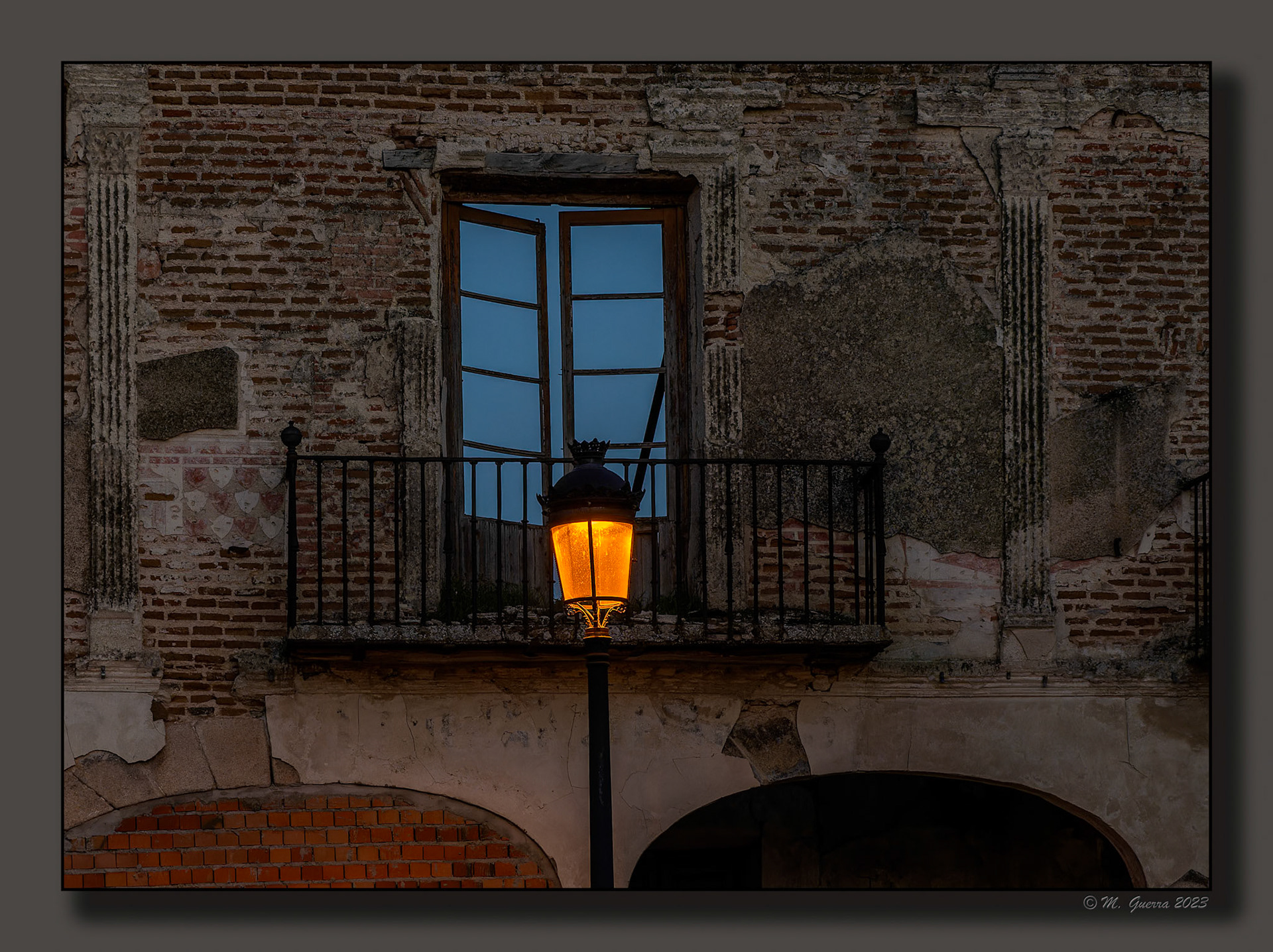 Farola iluminada frente a una casa en ruinas en Arévalo. 100ASA