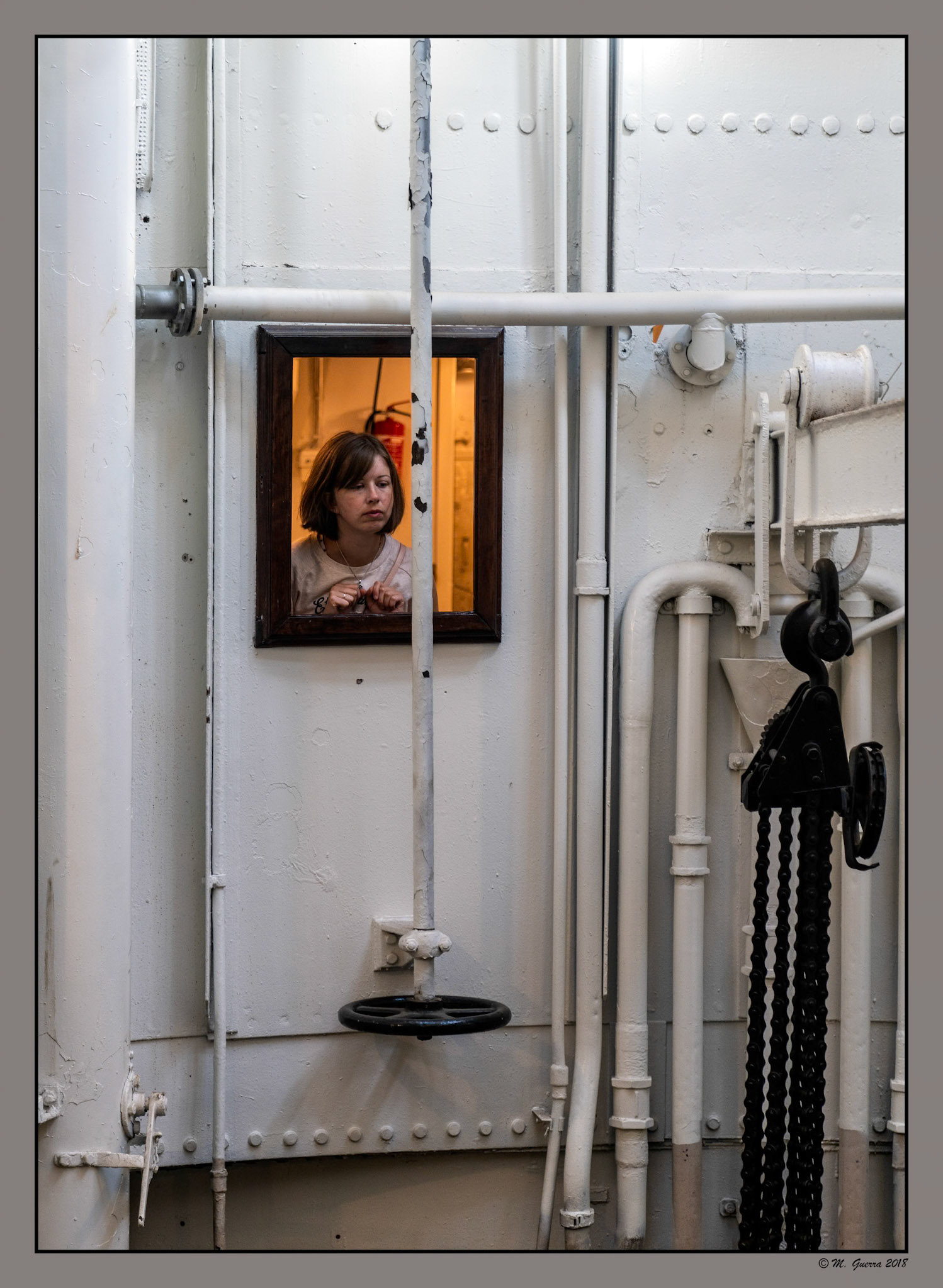 Chica en un ventanal de la sala de máquinas de un buque antiguo enTallin.Ampliar