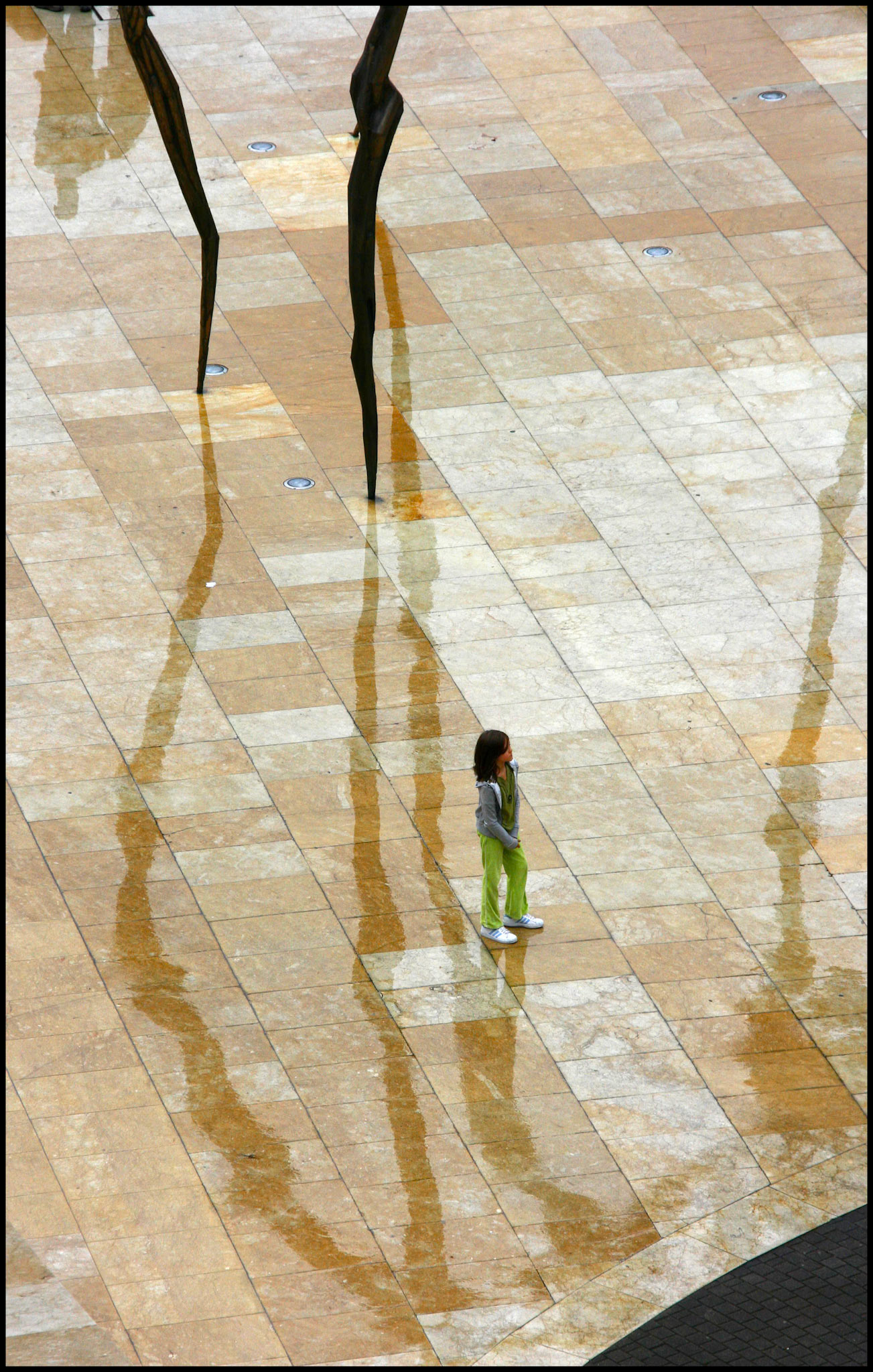Una niña en la escultura de la araña en el museo Gugenheim en Bilbao. Ampliar