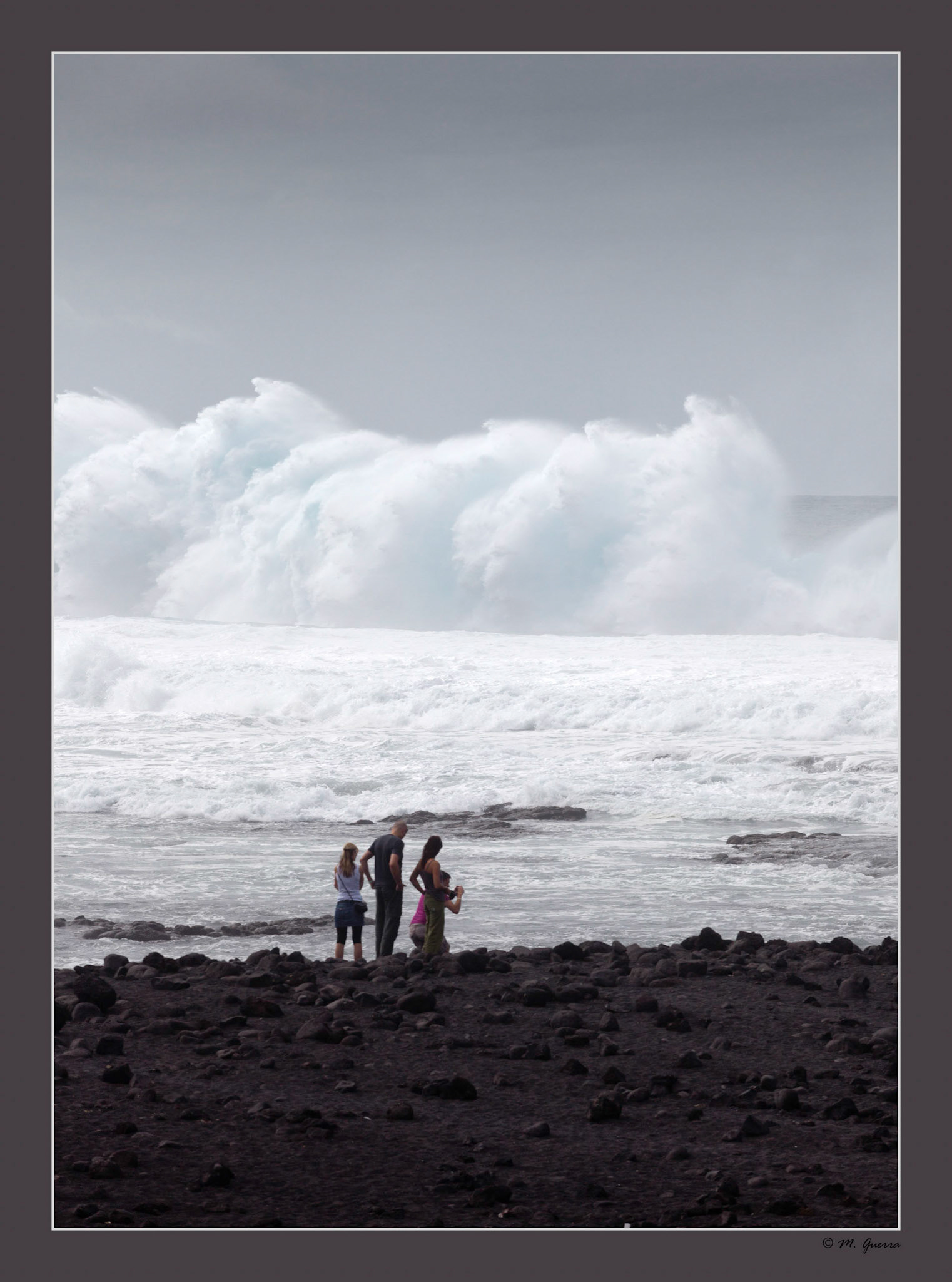 Turistas en La costa entre Los Hervideros y las Salinas en Lanzarote con unas enormes olas al fondo. Ampliar