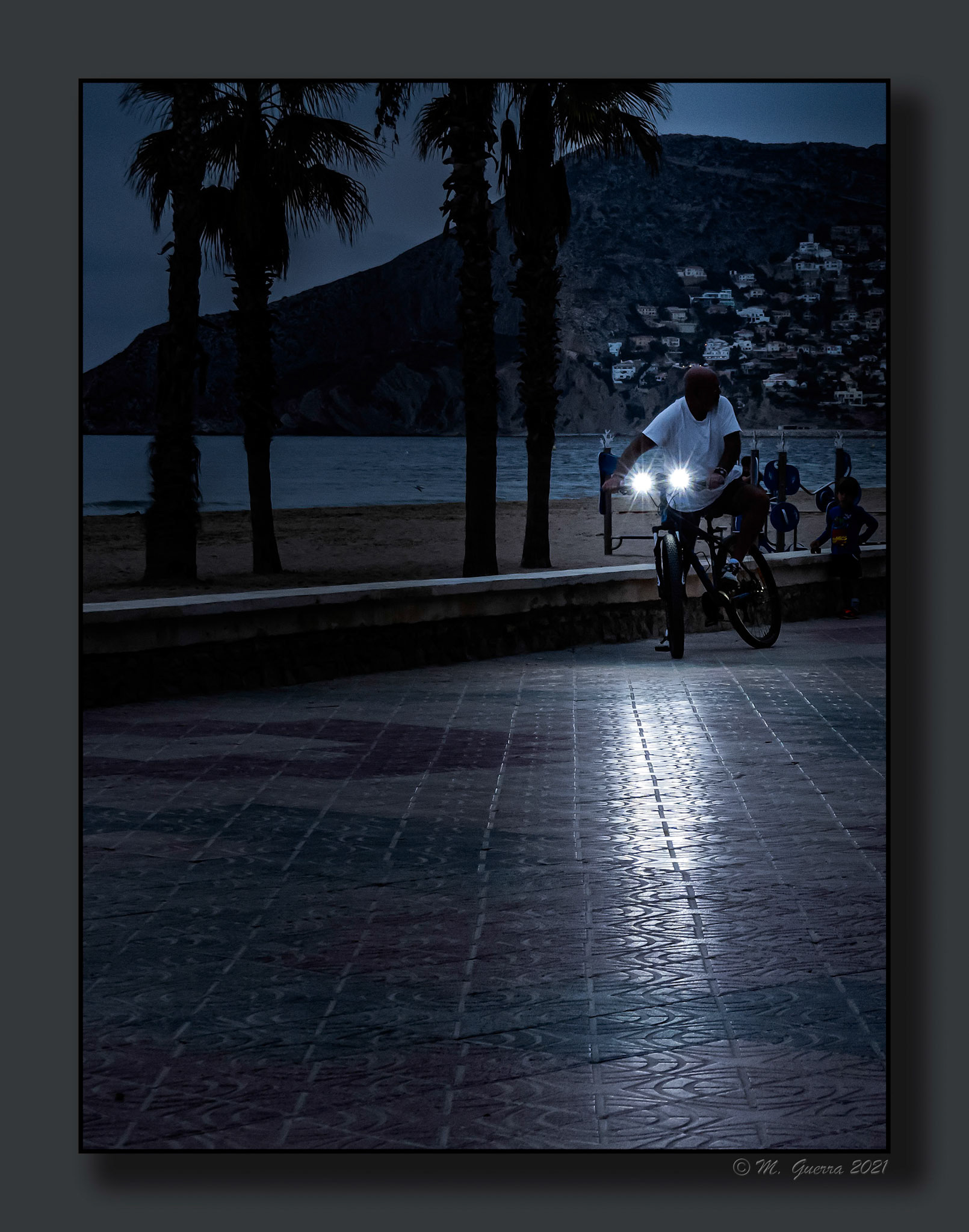 Hombre con una bicicleta con faros en e paseo marítimo de Calpe