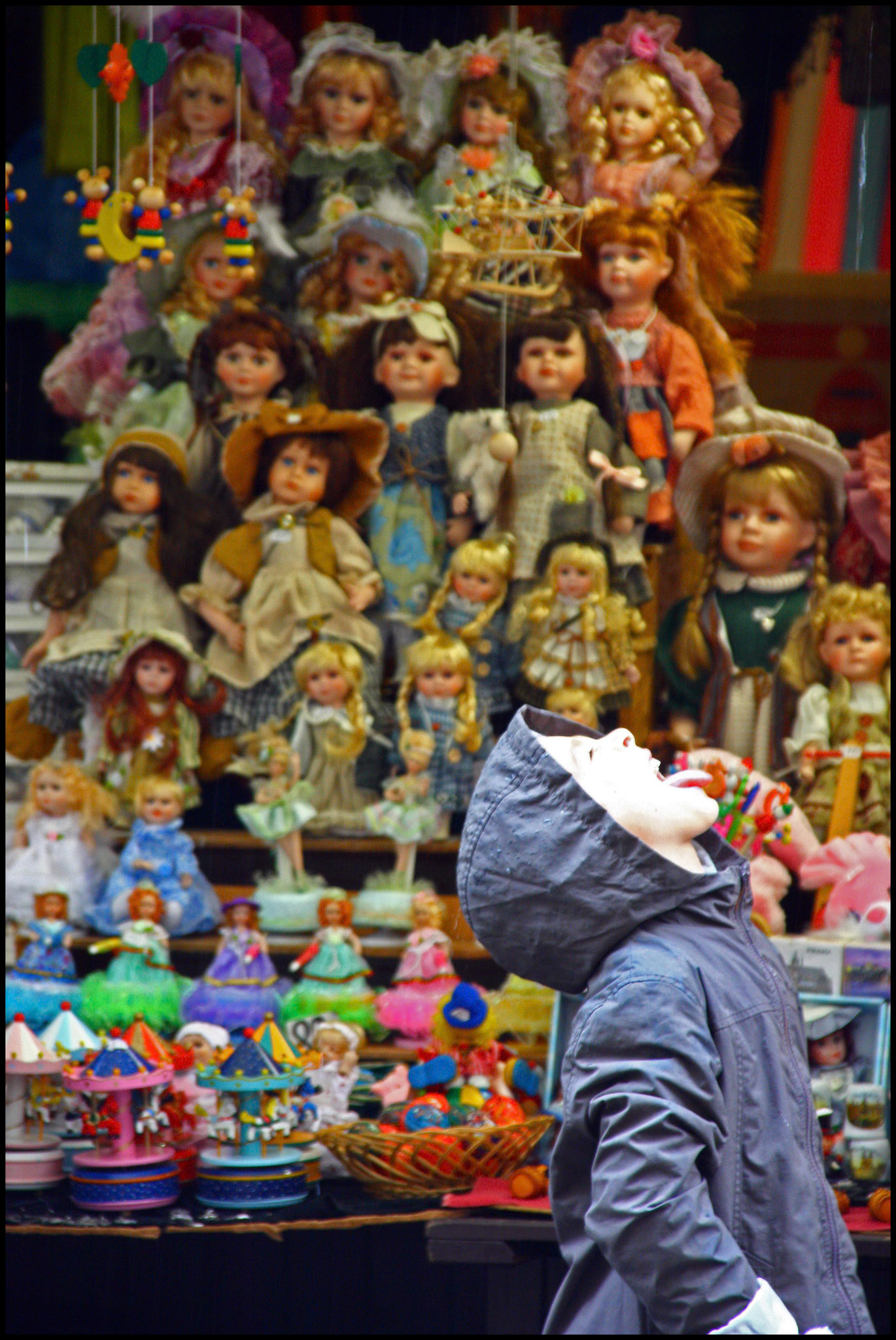 Niño bebiendo gotas de lluvia en un mercadillo en Praga. Ampliar