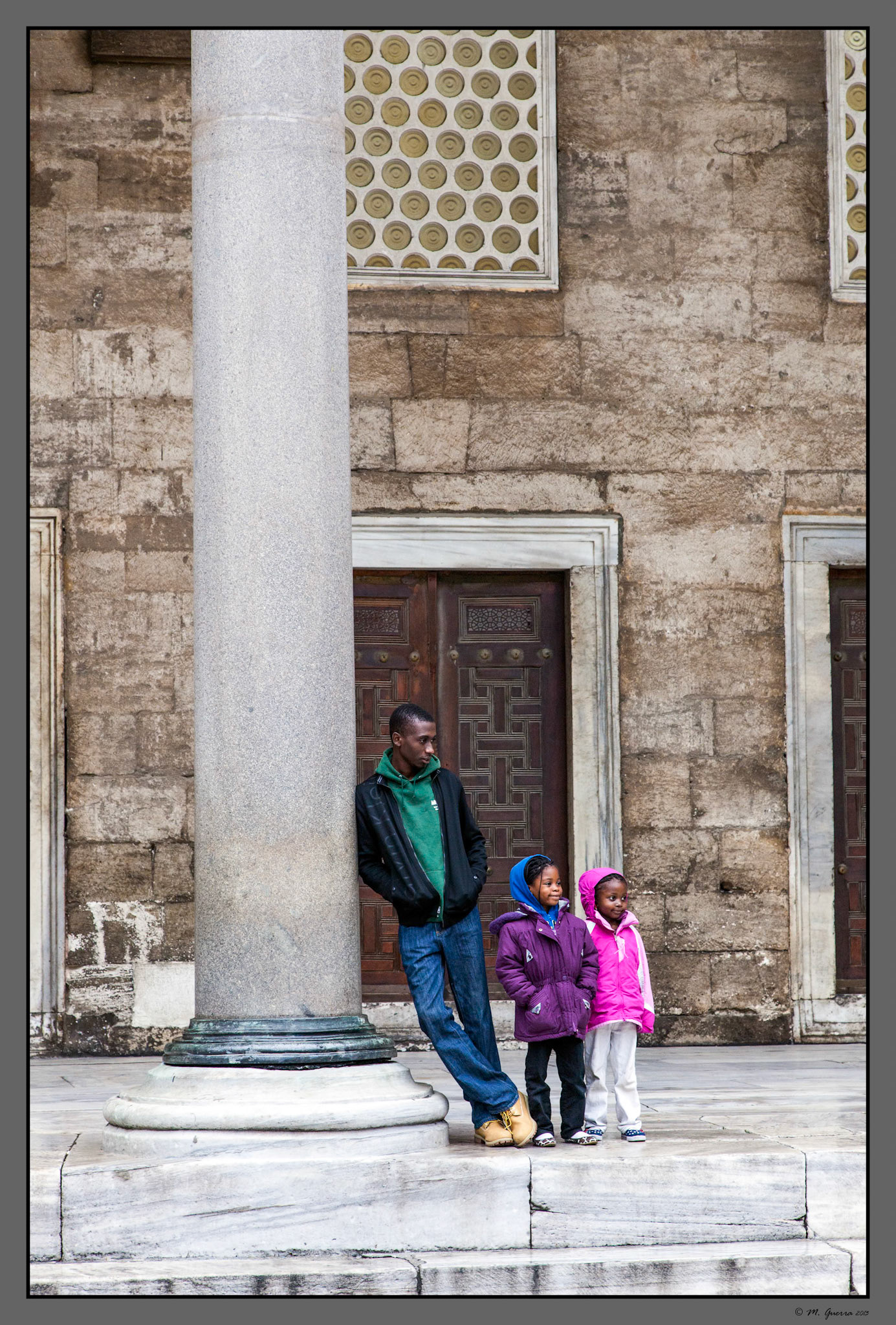 Padre con sus dos hijos en el patio de la mezquita azul de Estambul. Ampliar