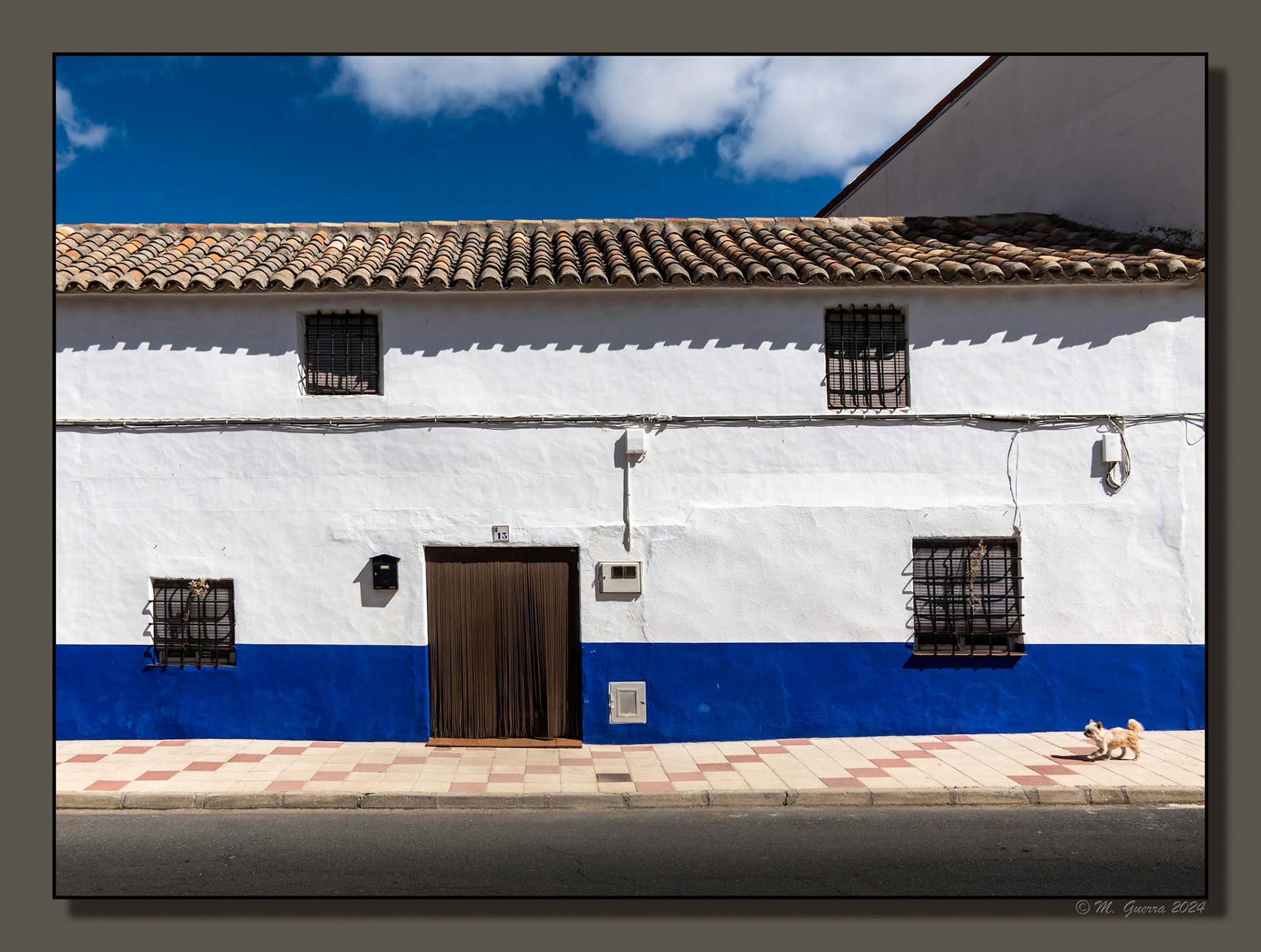 Casa encalada y franja azul con perro en Almonacid de Toledo