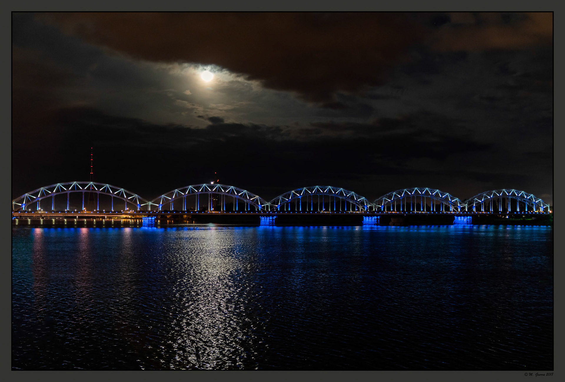 Puente de tren ferroviario en Riga iluminado. Ampliar. 100ASA