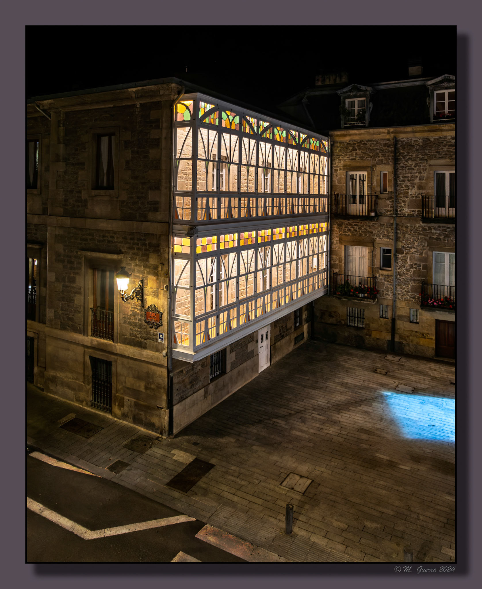 Casa con galería iluminada de noche en Vitoria