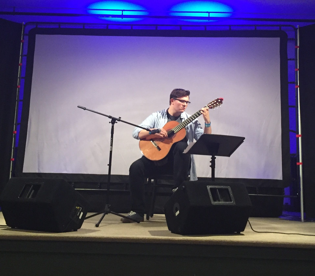 Isaac Brady performing an acoustic guitar solo in a live indoor venue.