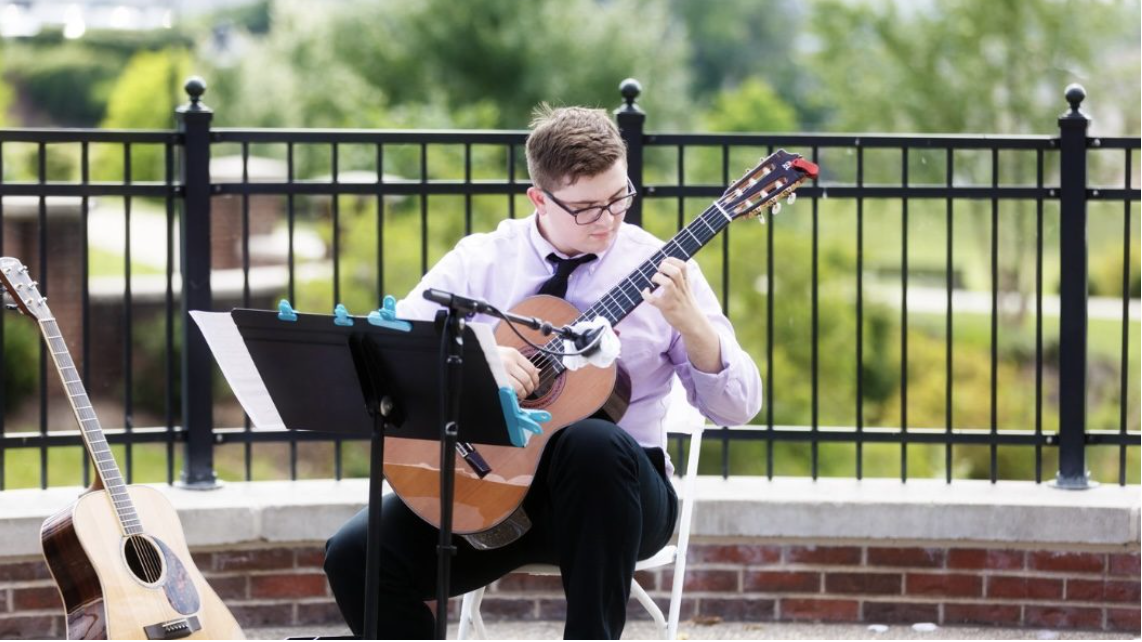 Isaac Brady performing an acoustic guitar solo at an outdoor venue.