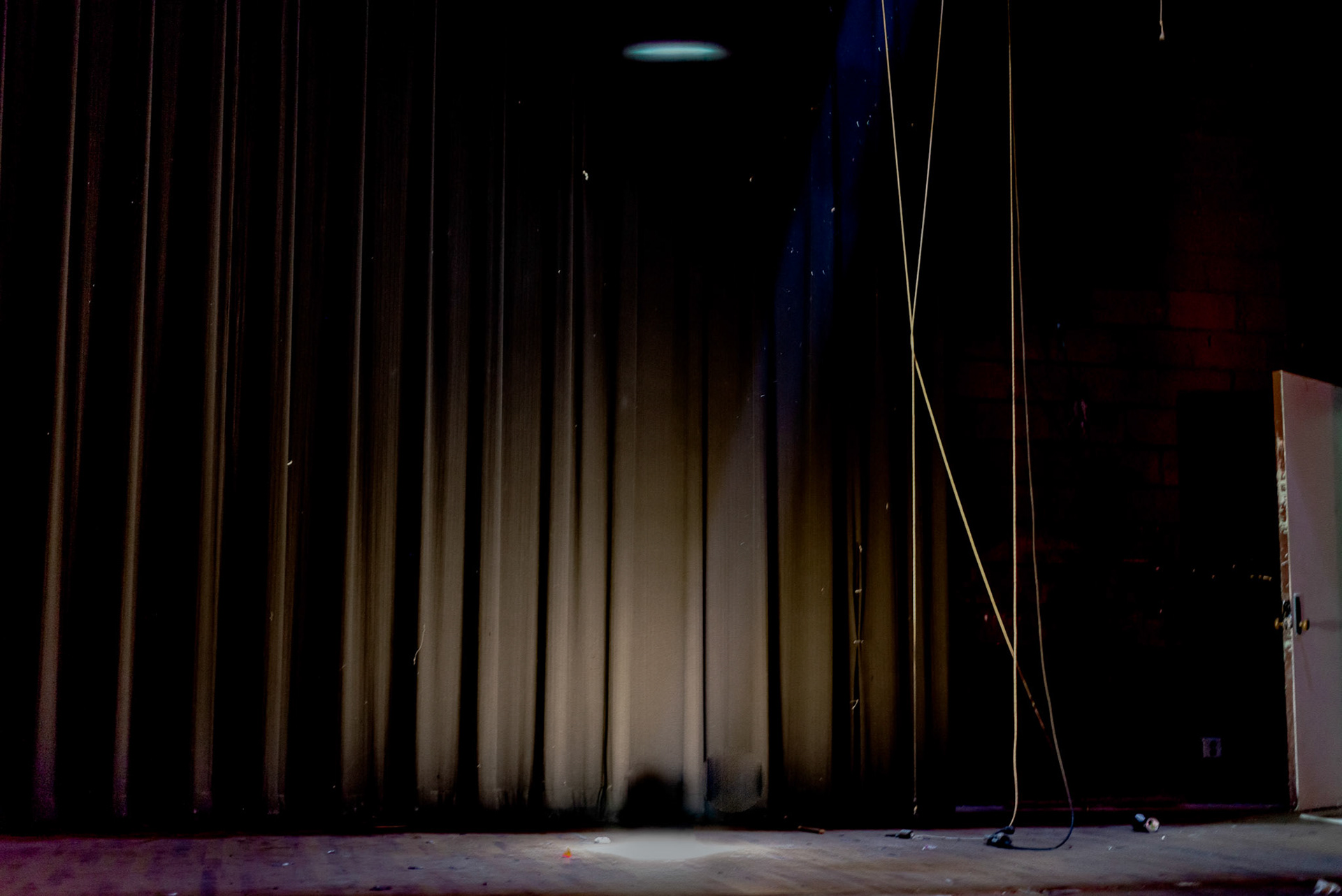 Debris and light fall on the abandoned stage in the old Williston High School.