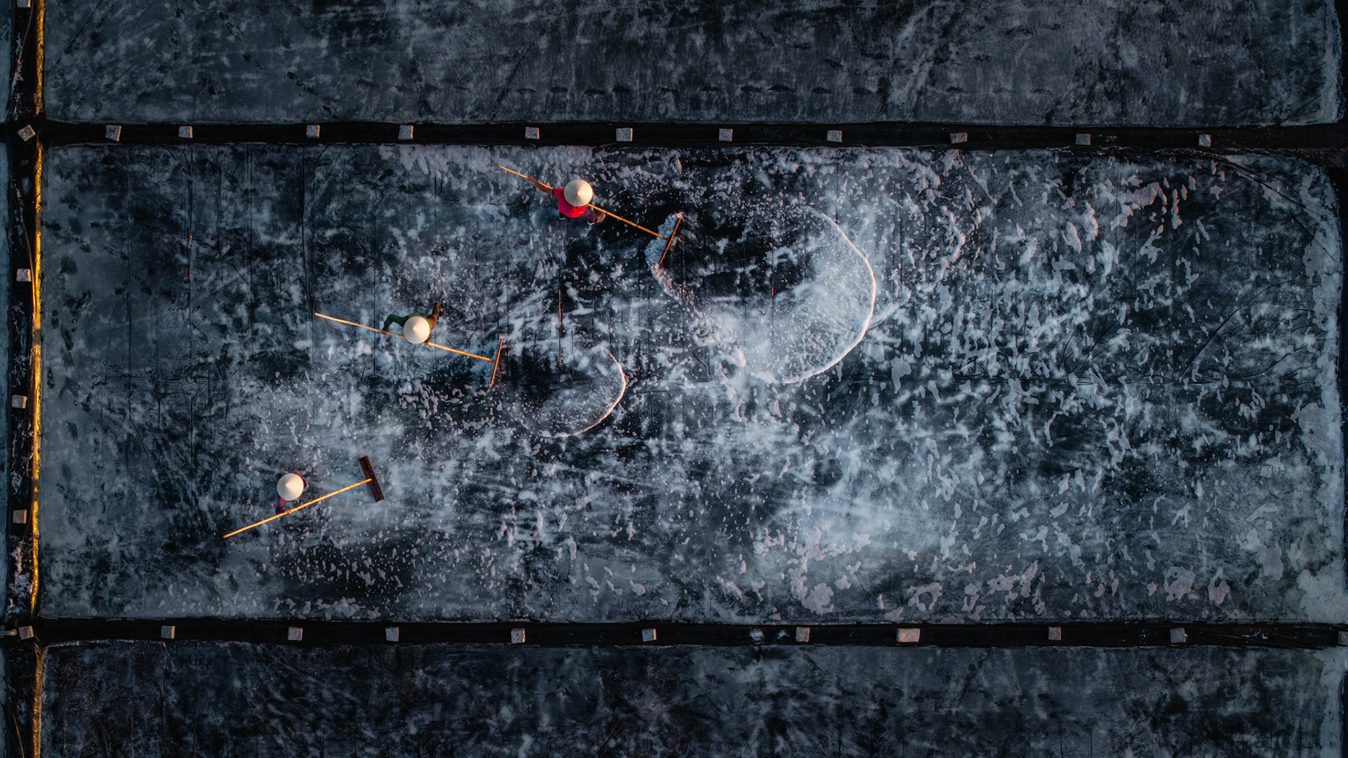 The stark contrast of brilliant white salt against the deep black plastic lining creates a stunning optical illusion from the air.