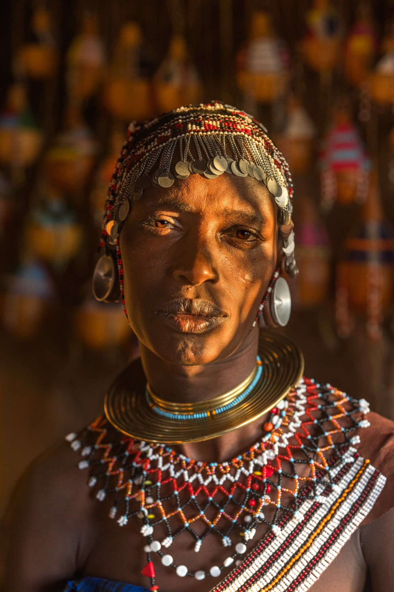 Gilded by the Sun — The golden hour light accentuates the warm copper tones of this woman's skin and brass jewelry. Her expression holds a quiet dignity characteristic of Datoga women, glowing with a resilience that mirrors the harsh beauty of the savannah.