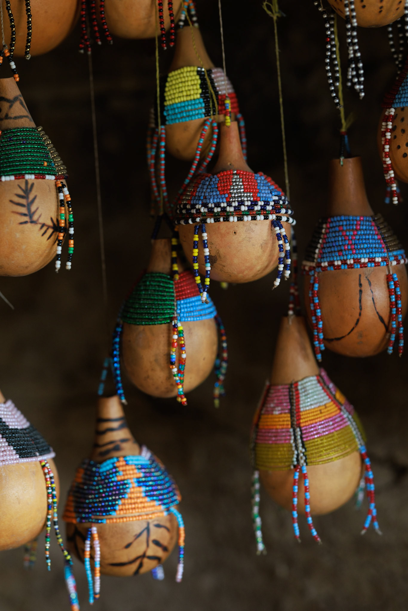 Vessels of Life — Traditional milk gourds, decorated with leather and delicate beads, hang ready for use. These vessels are central to the pastoralist lifestyle, essential for storing the milk that sustains the tribe, symbolizing the deep connection between the people and their herds.