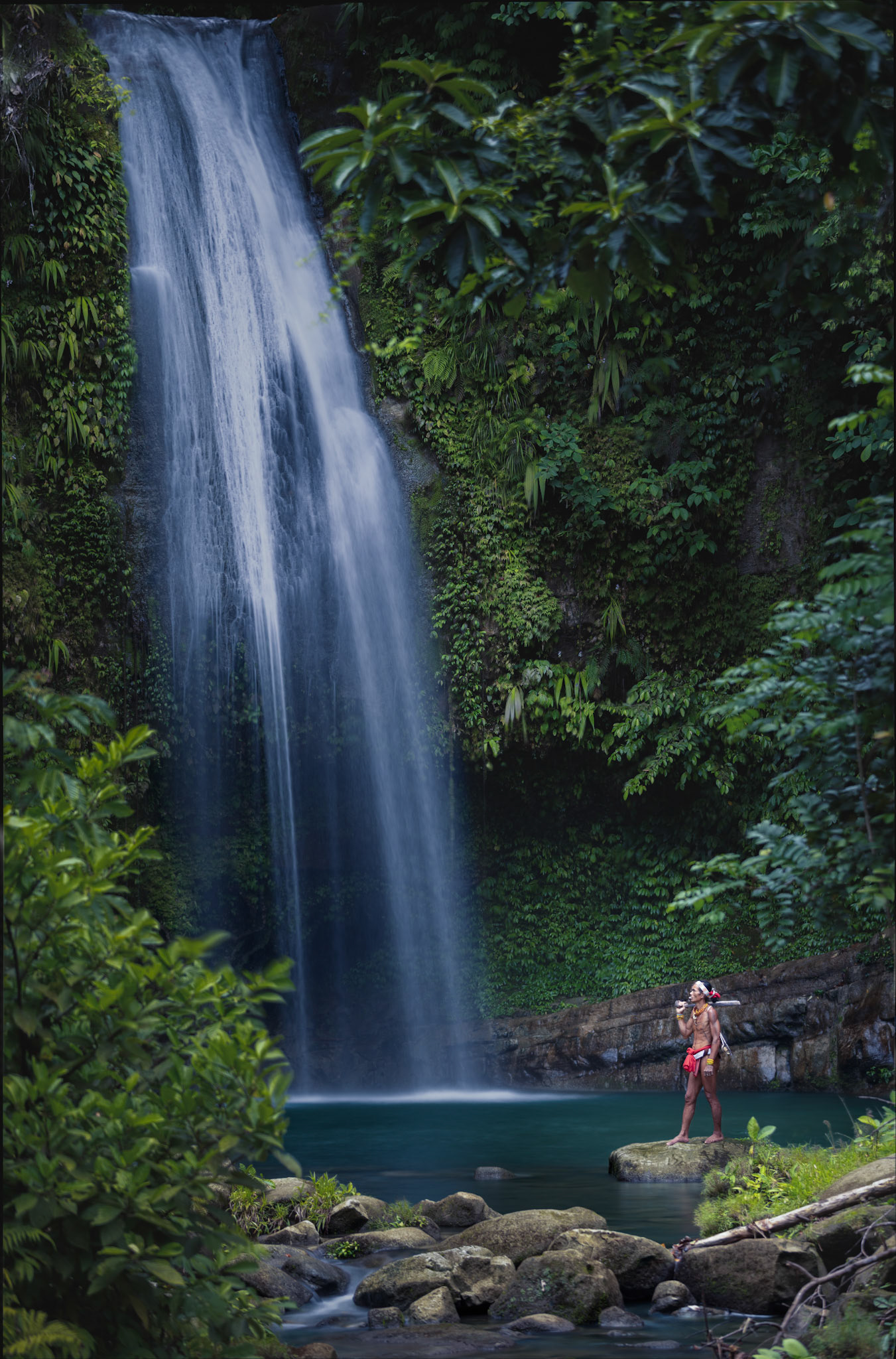 The Jungle's Vein — A majestic view of the waterfall cutting through the dense canopy. This fresh water is the lifeblood of the island, nourishing the sago palms and medicinal plants that the Mentawai people rely on for their survival.