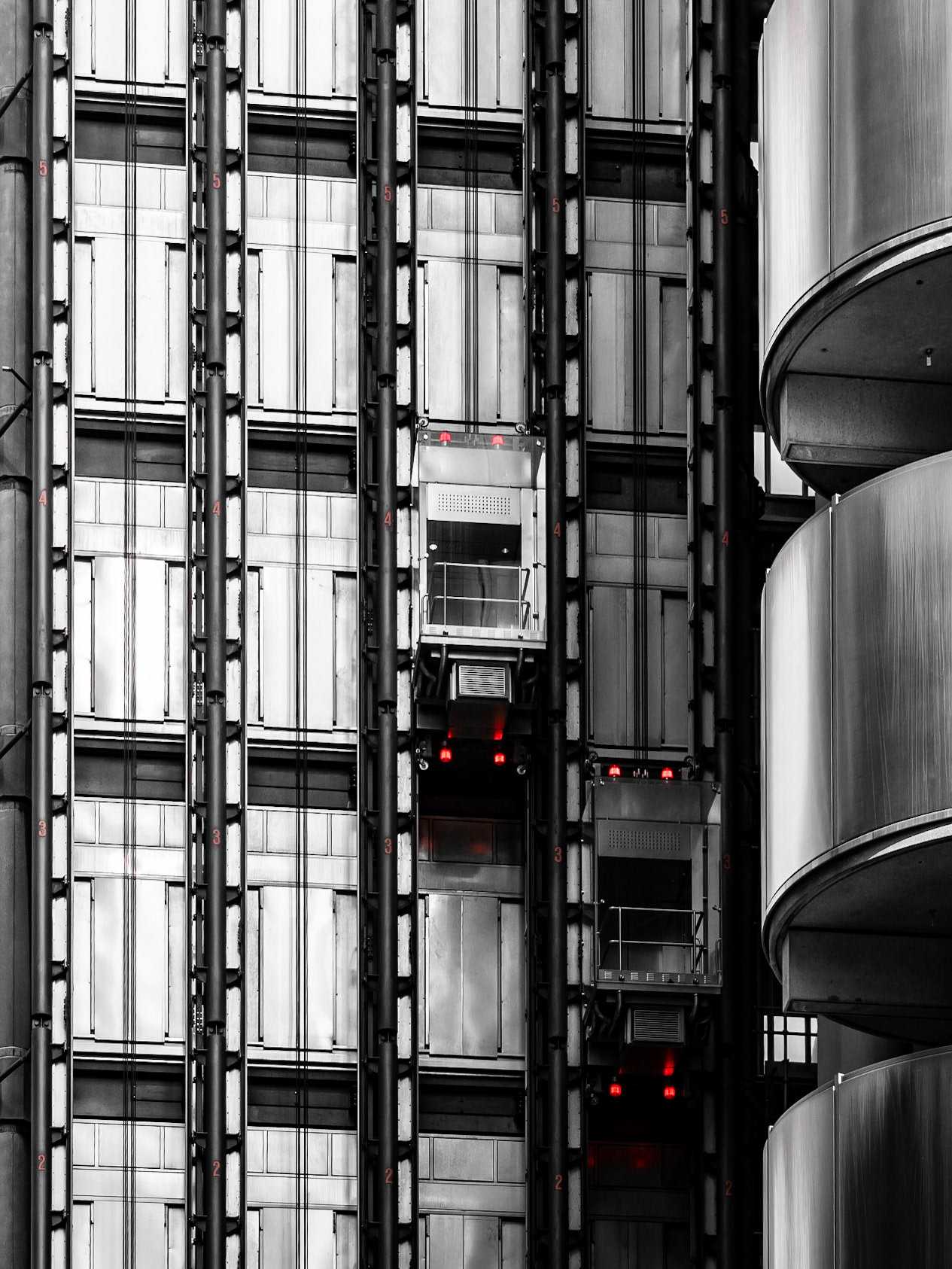 A pair of lifts hang to the shiny steel side of the modern Lloyds Building in the City of London