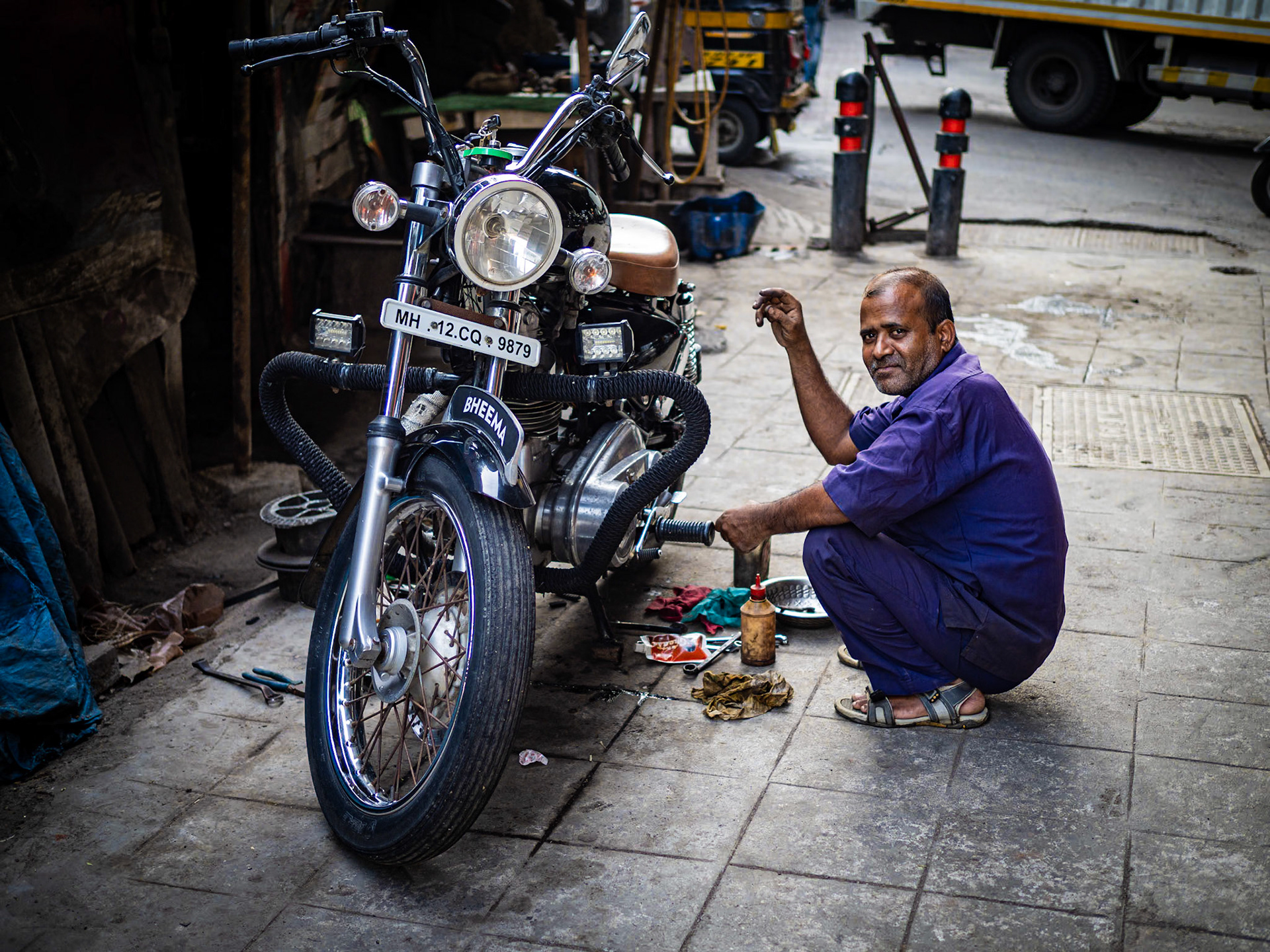 A Mumbai resident tinkers with his motorcycle, his pride and joy