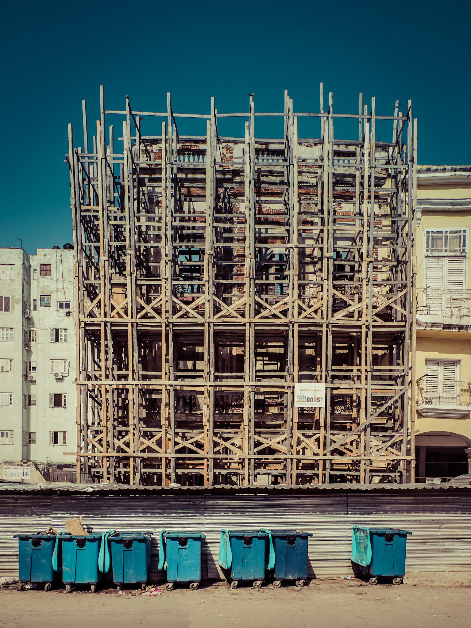 A collection of waste bins stand in front a building undergoing restoration in the Cuban capital of Havana