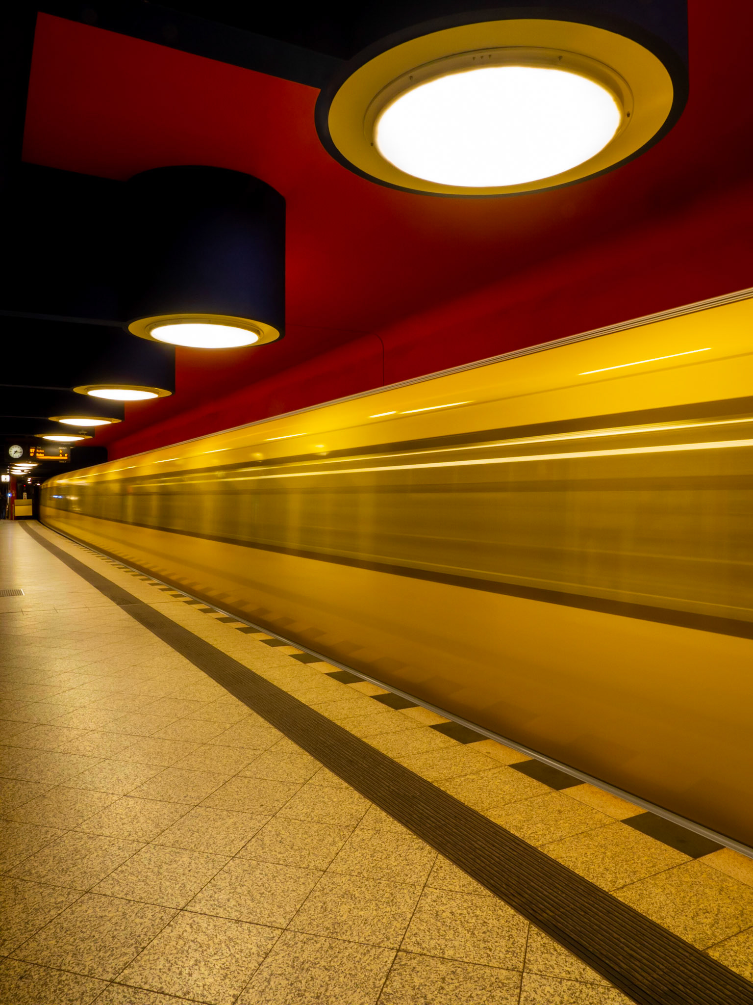 A metro train races through a colourful U-Bahn station in the city of Berlin