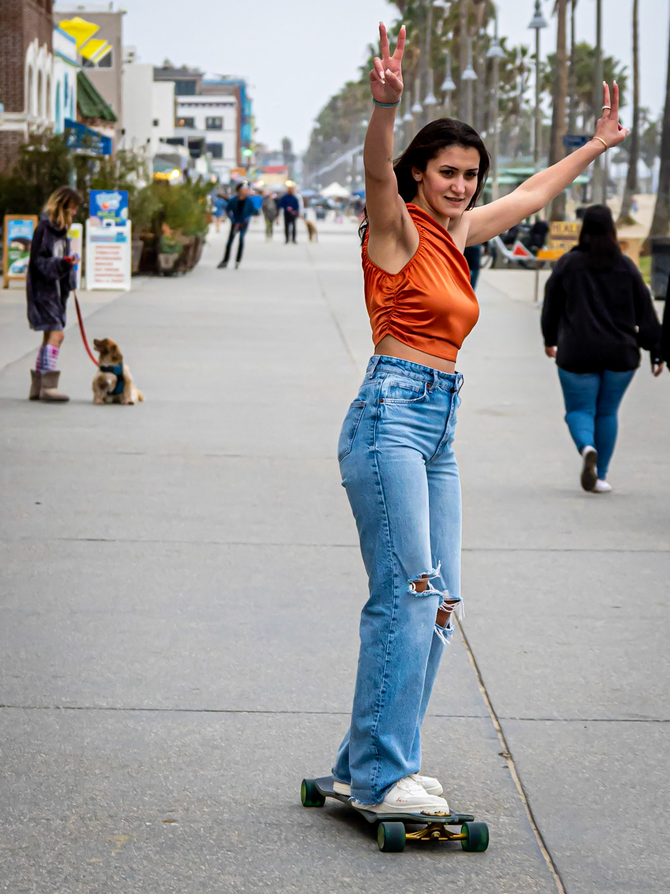 A young woman is pleased with herself after successfully completing her latest skateboarding trick on the beachfront in Venice in Los Angeles