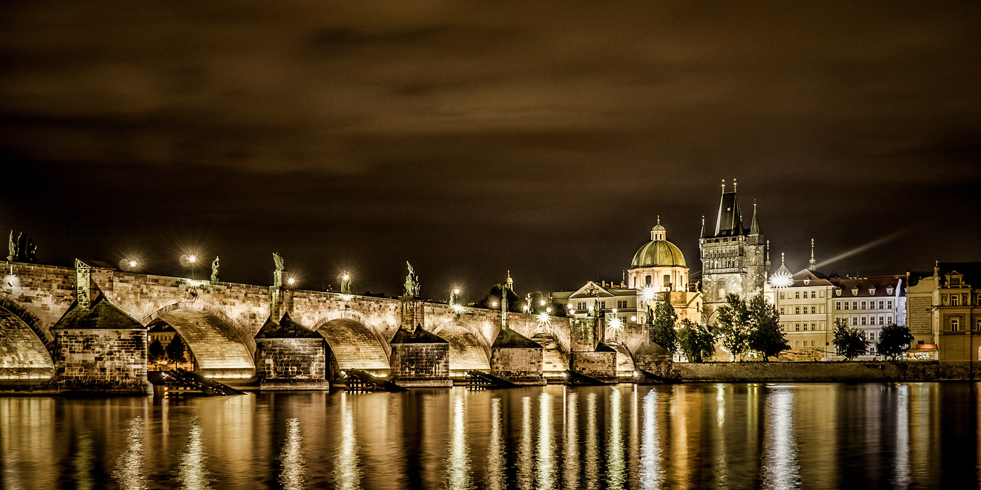 The 14th-century Charles Bridge lit beautifully under a night sky in Prague