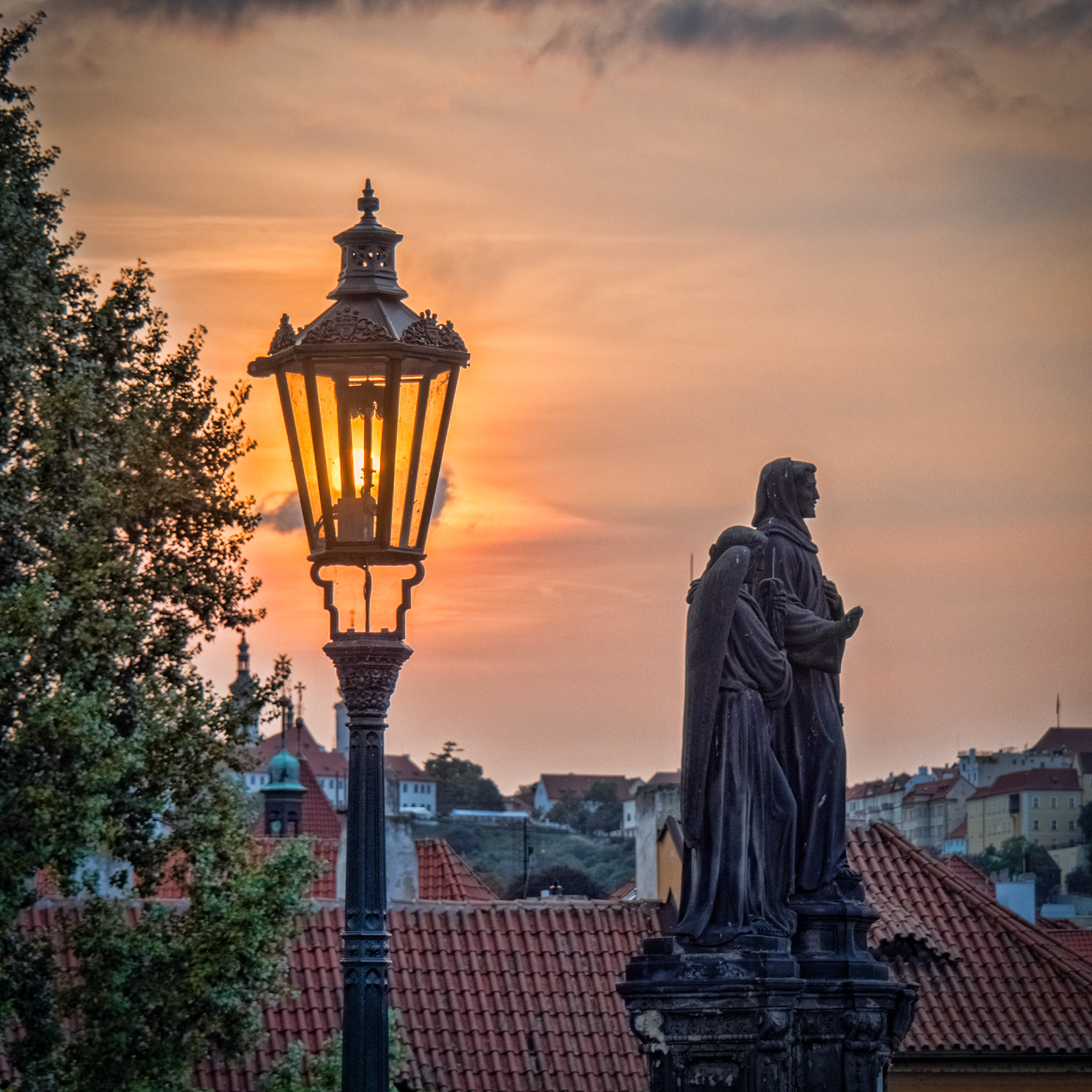 A setting sun shines through a street-light on the famous Charles Bridge in Prague