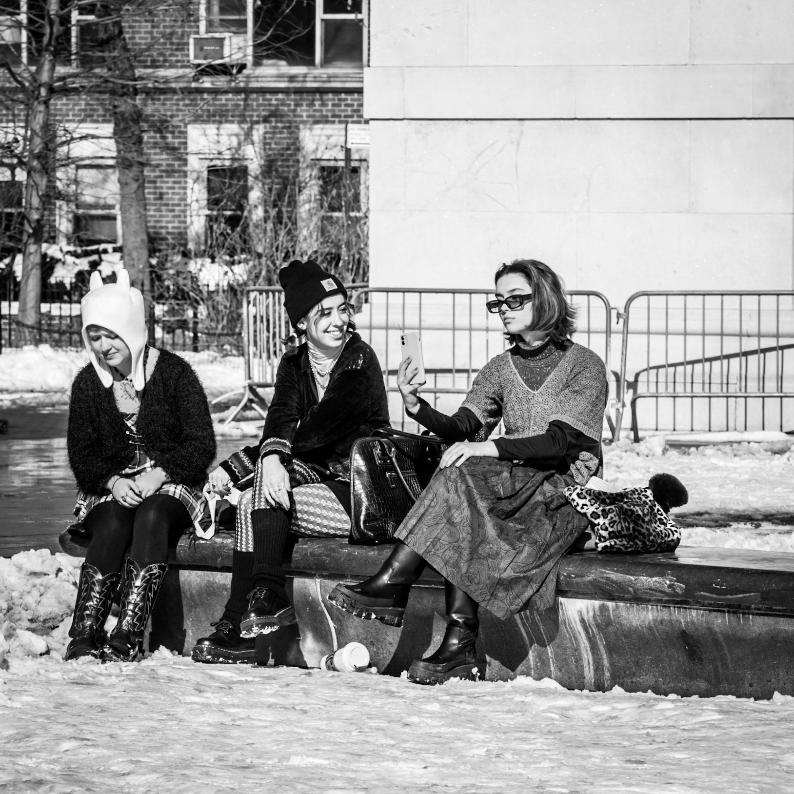 A friend looks on whilst a woman seeks the perfect pose for a selfie in New York's Washington Square Park