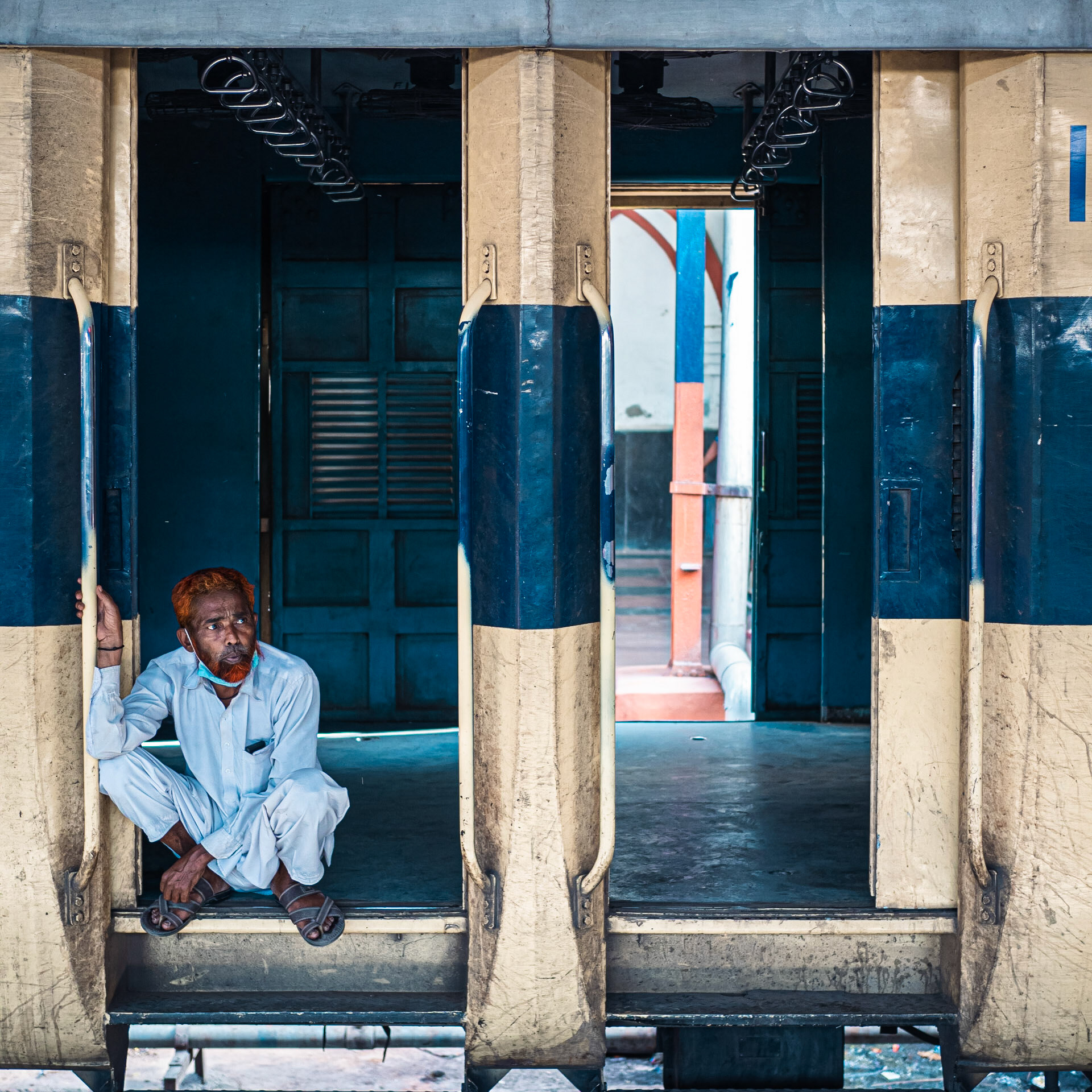 A lone man squats in the doorway of a railway carriage as he awaits his train's departure from Old Delhi railway station