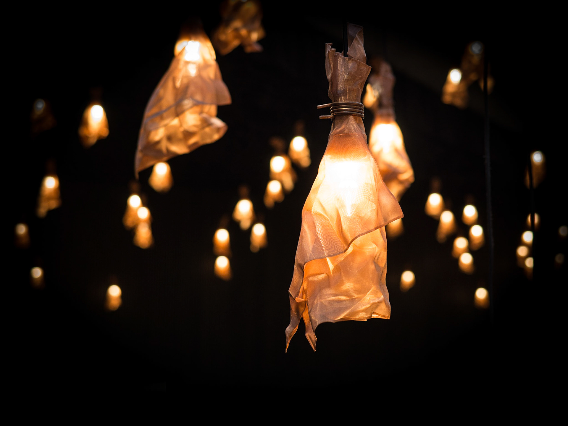 A contemporary art installation made of hand-shaped copper lanterns