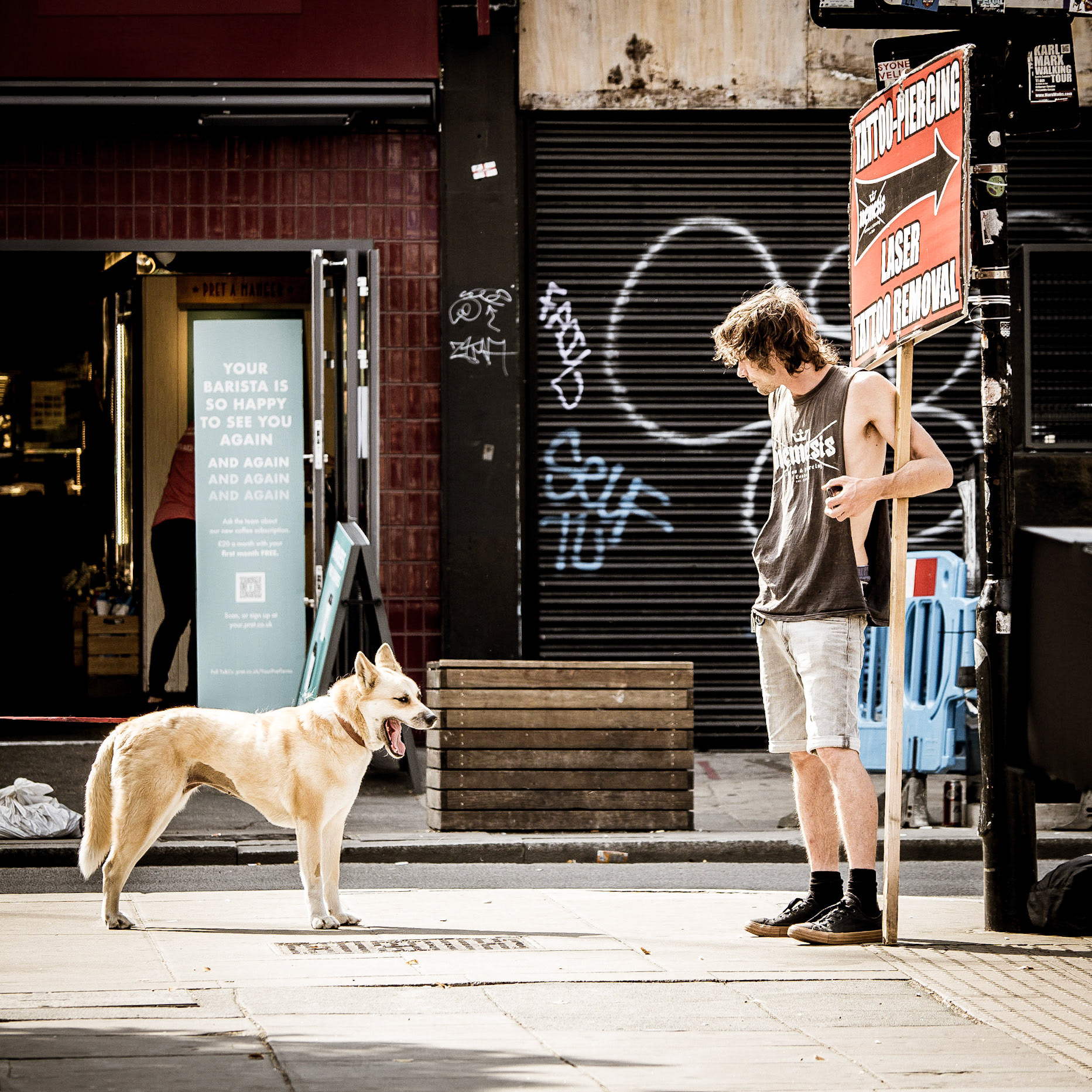A dog and a man stand their ground when competing for space on Camden High Street, London