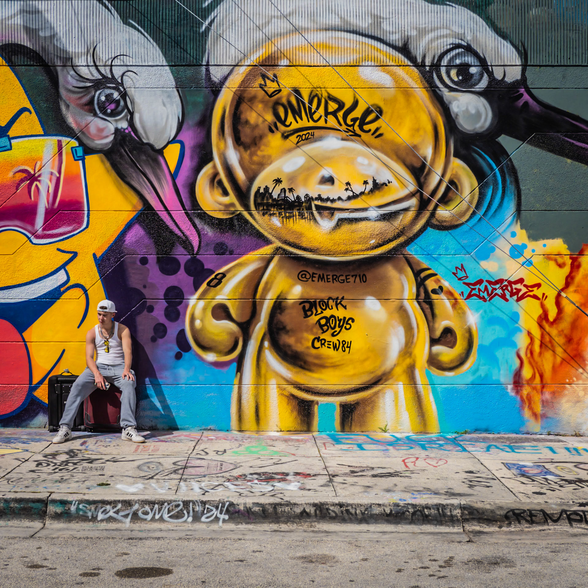 A traveller waits for his ride in front of a mural in the Wynwood district of Miami