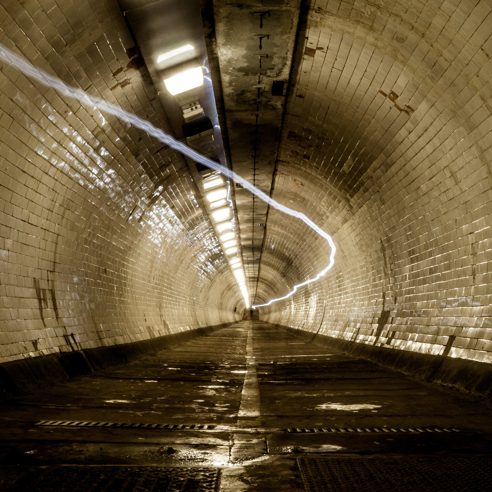 The light trail of a cyclist passing through the Greenwich Foot Tunnel, passing under the River Thames in London