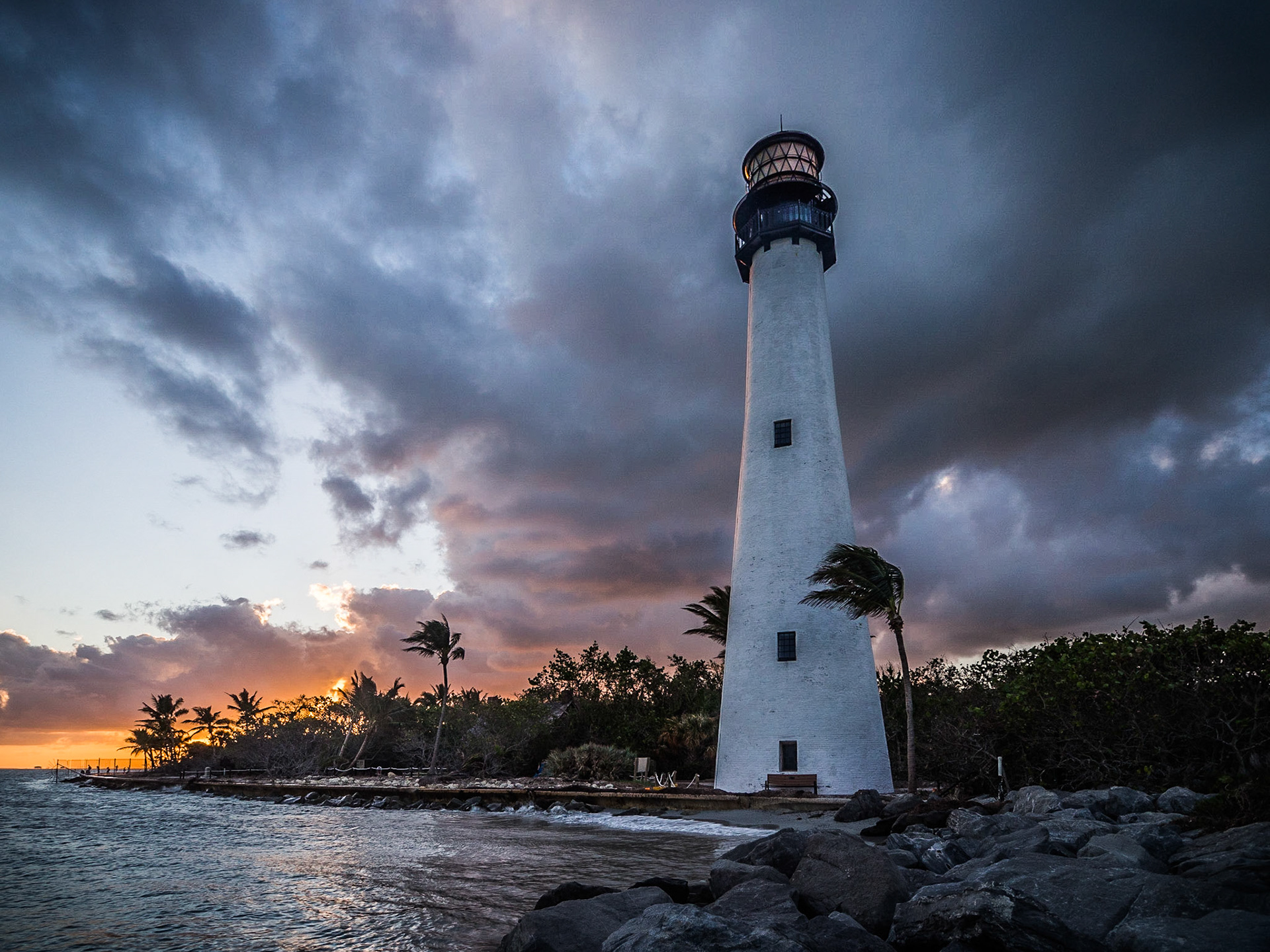 The sun sets as a thunderstorm passes behind the Cape Florida lighthouse on Key Biscayne, Miami