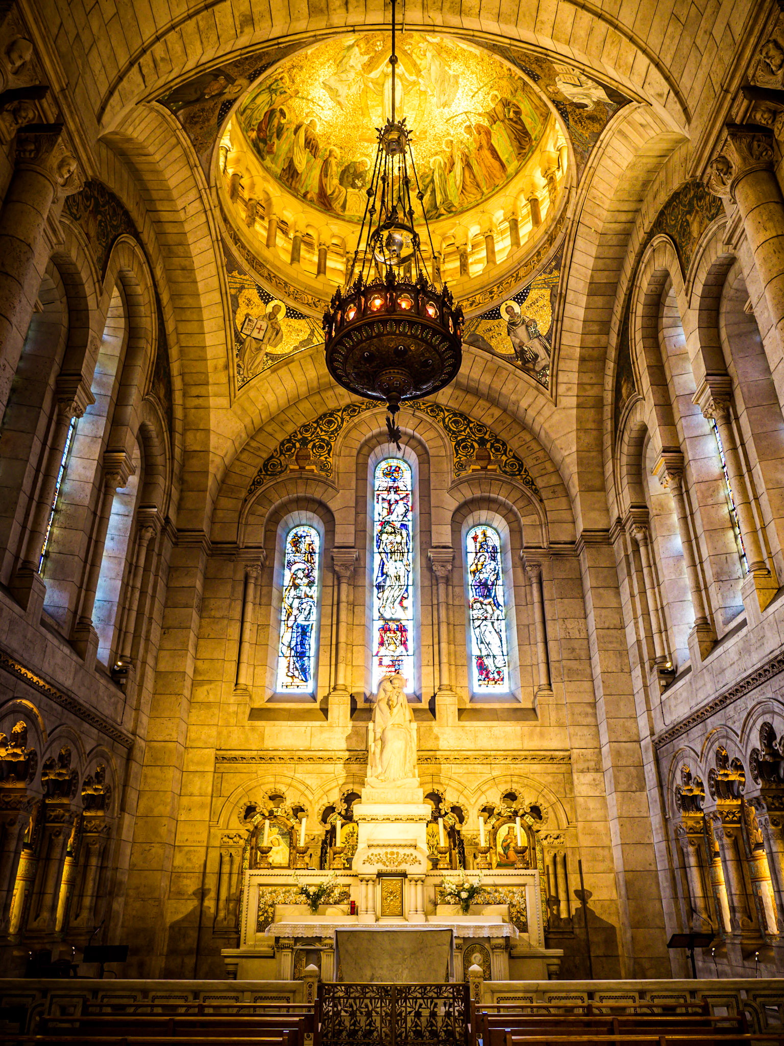 Ornate stained glass window sit above the alter in the Sacre-Couer cathederal in Paris