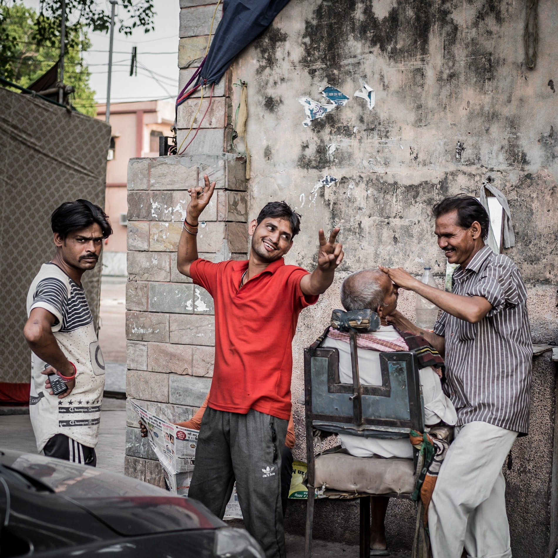 Customers practice their bowling technique whilst waiting for a shave in the Chandni Chowk market district of New Delhi