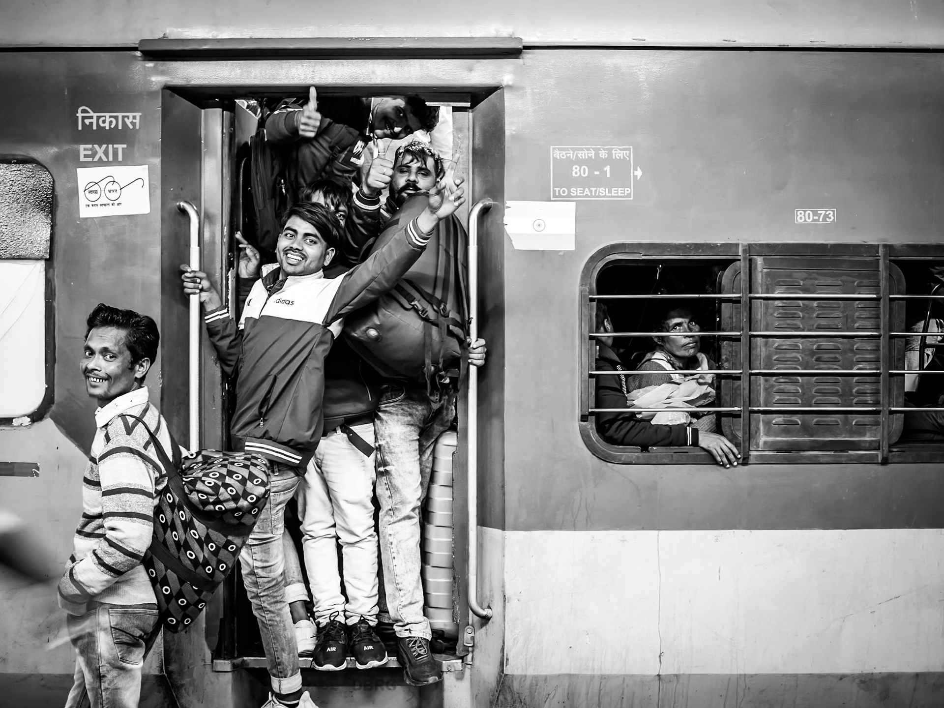 Commuters celebrate finding their space on board a packed train out of Old Delhi railway station