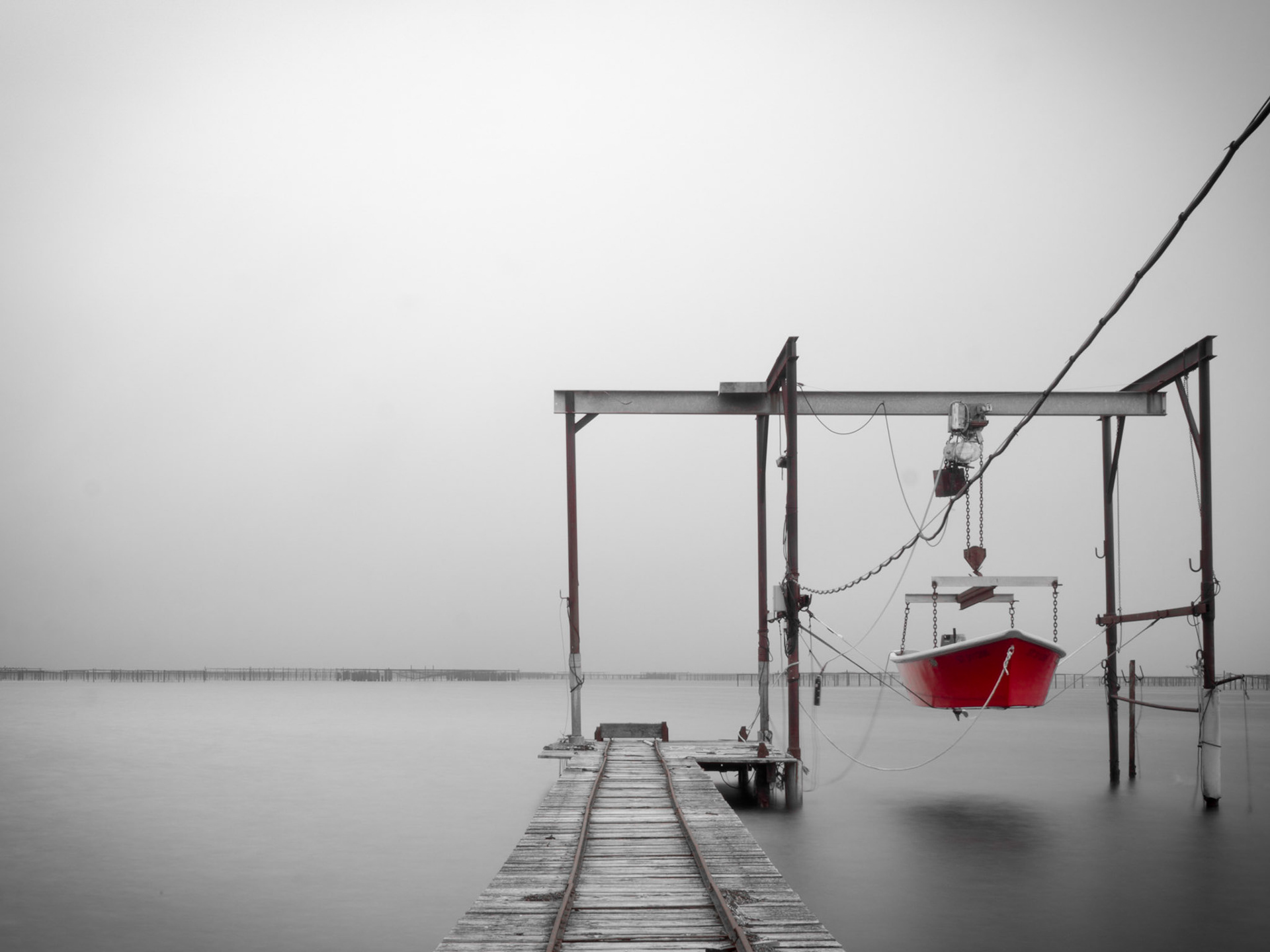 A lone fishing boat raised out of the water as a storm approaches over oyster beds near Méze, southern France
