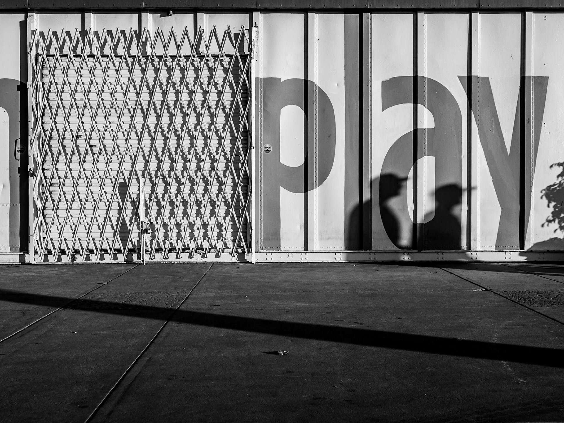 A setting sun casts deep shadows of passers-by against a storage container just off Santa Monica beach