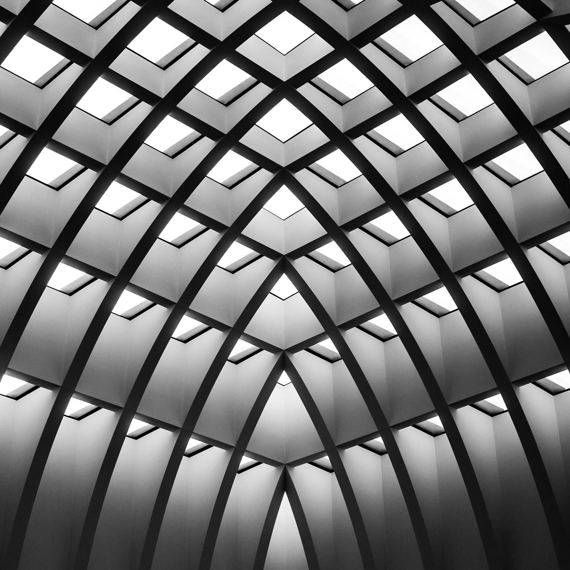 A bright sky shines through the latticed arches of an atrium in central Berlin