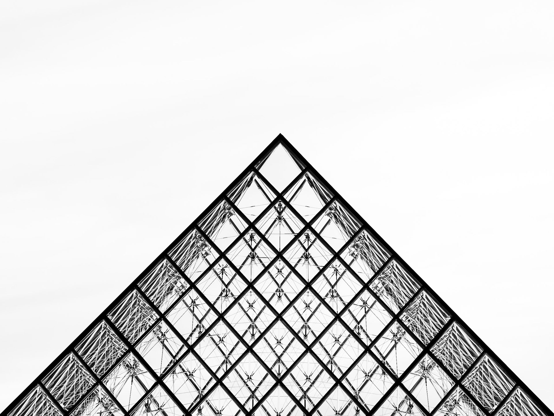 The modern glass pyramid sits above the histpric Louvre Museum in Paris as the sun sets behind