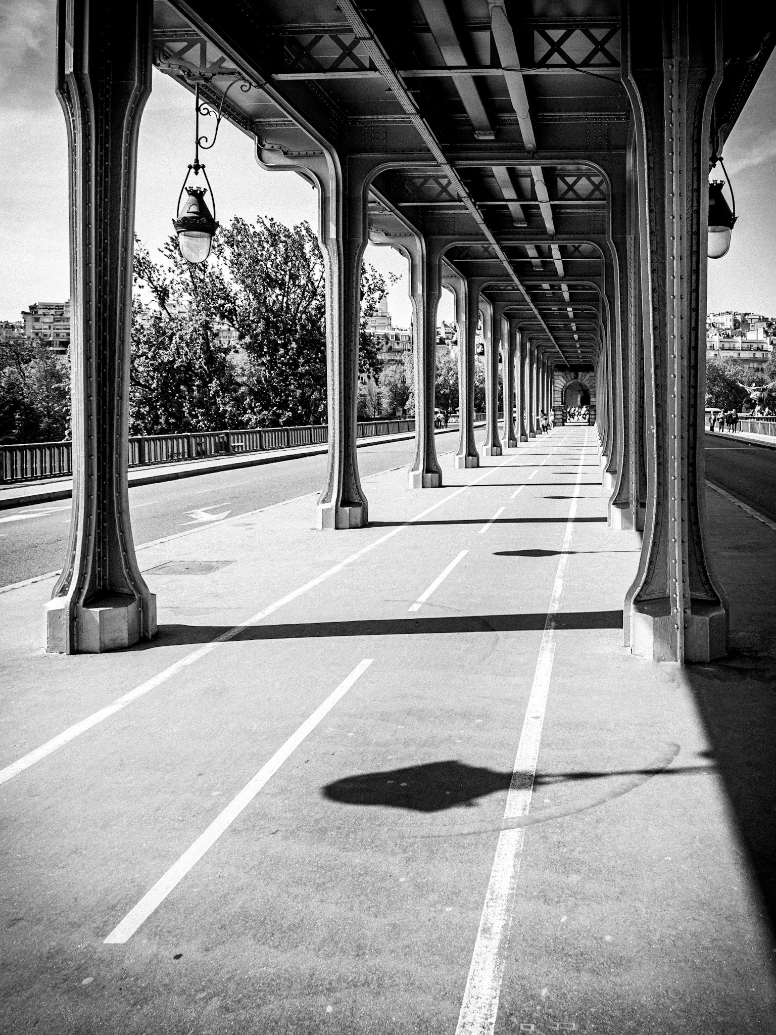 A cycle path in Paris mirrors a metro line above as the tracks pass over a bridge in central Paris
