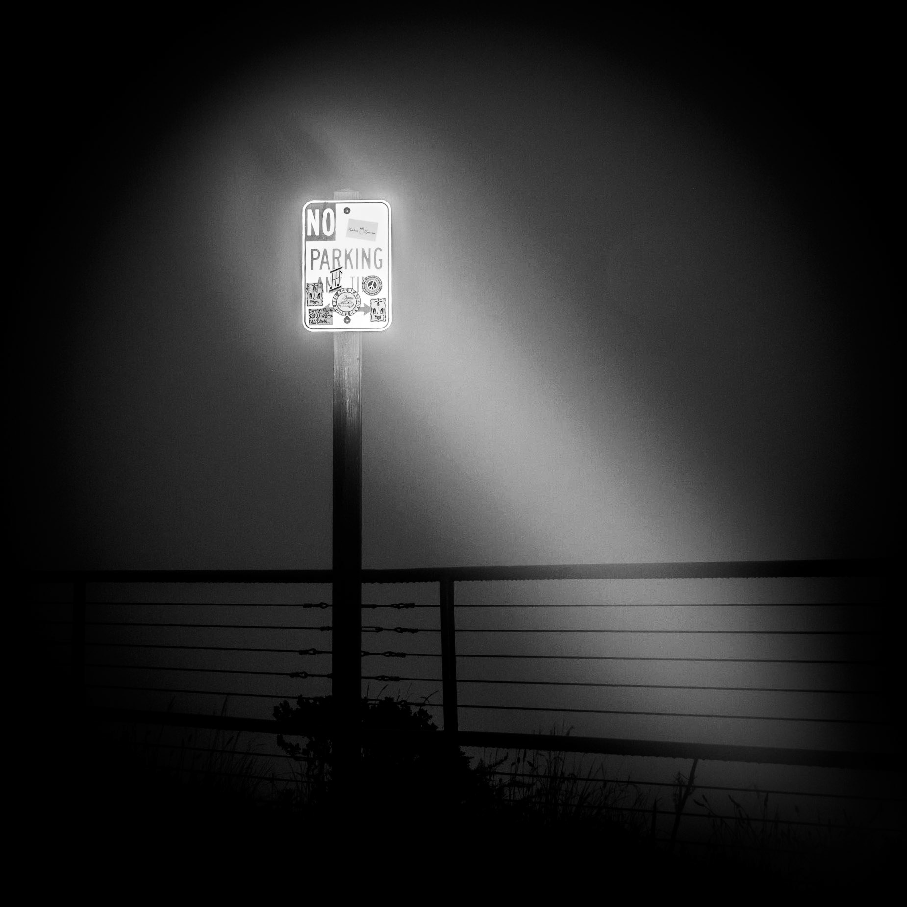 A No Parking sign emerges from the fog immersing the hills that surround the Golden Gate Bridge, San Francisco