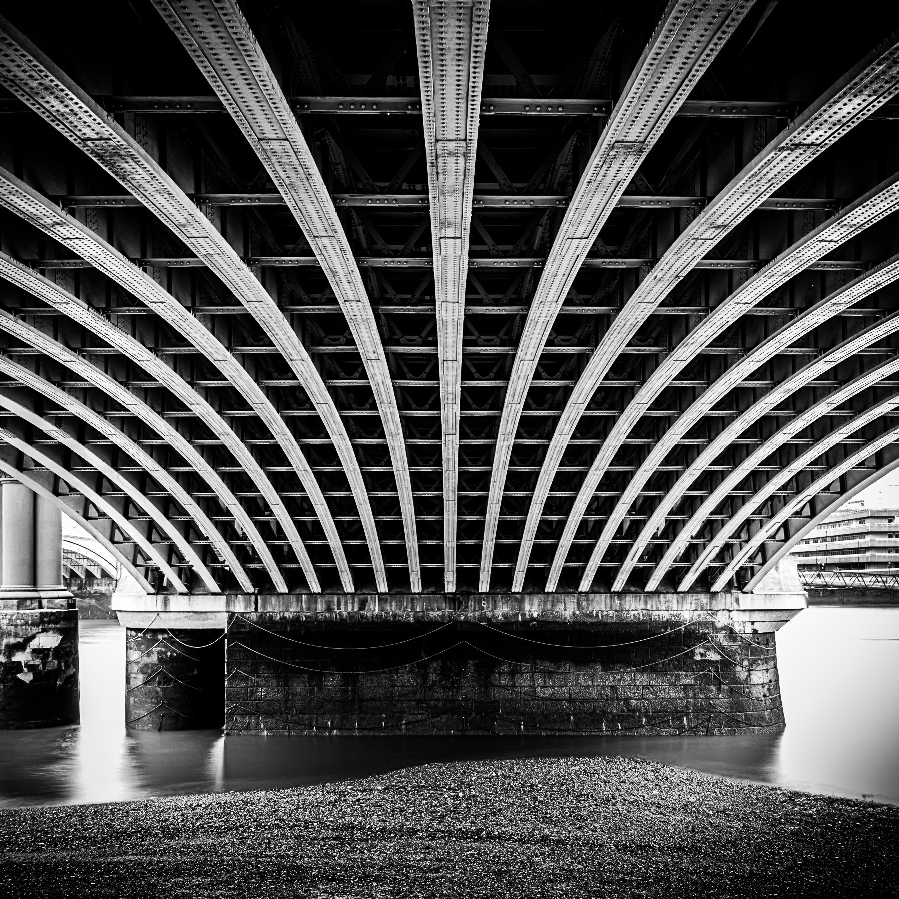 Sweeping girders hold up Blackfriars Bridge at low tide on the River Thames