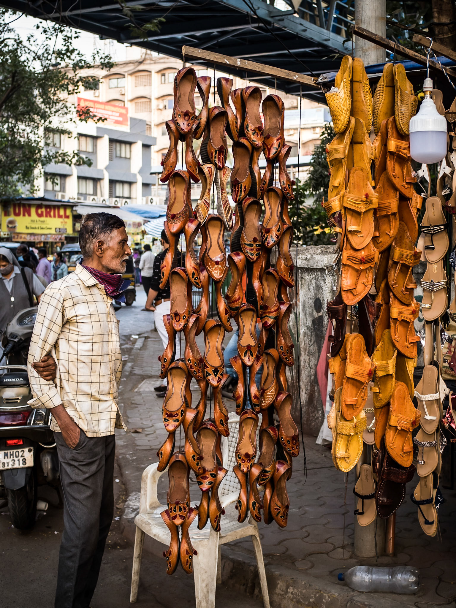 A shoe-maker watches over his latest collection of shoes for sale in a street market in Mumbai