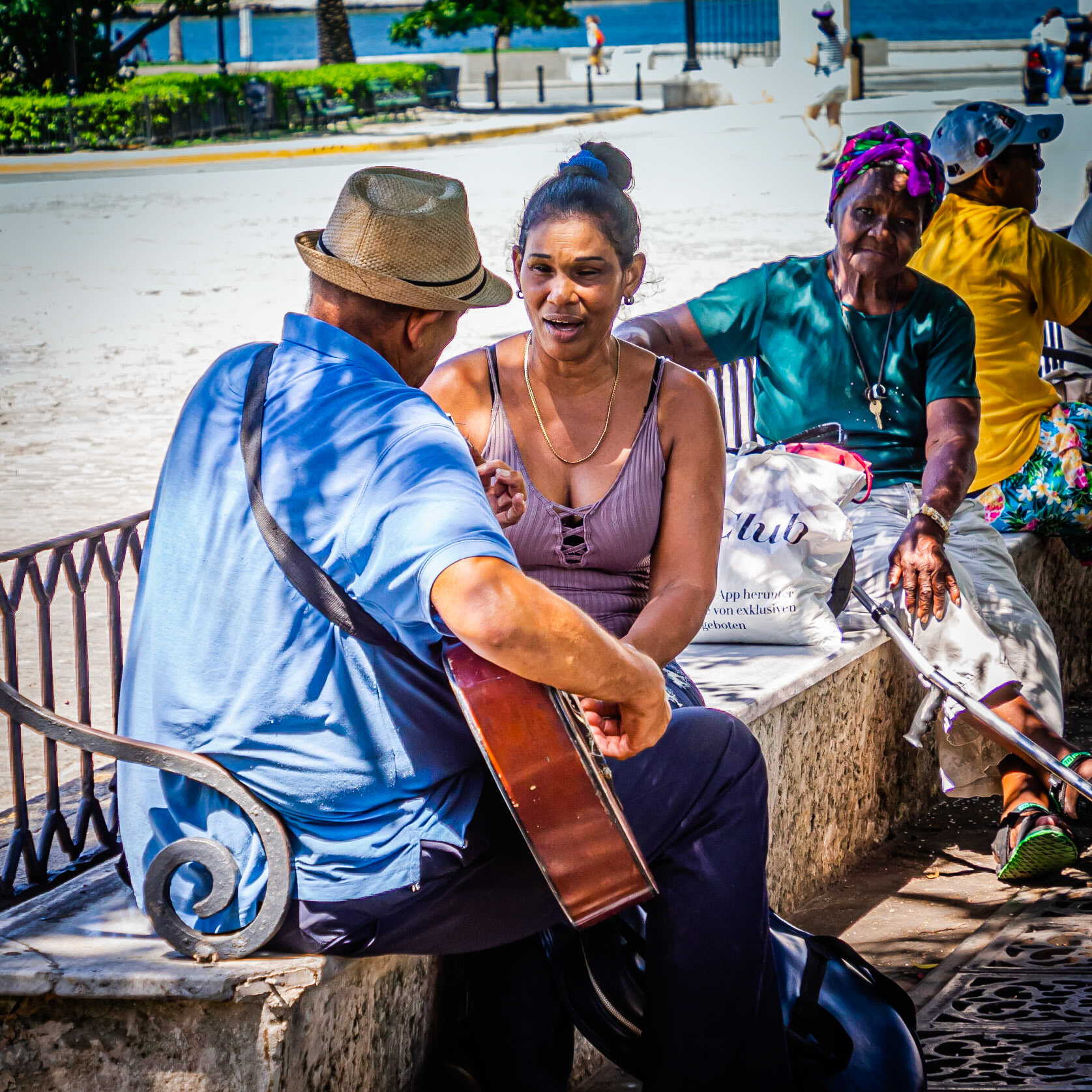 A guitarist accompanies a woman singing love songs under a tree in the Plaza de Armas in Havana, Cuba