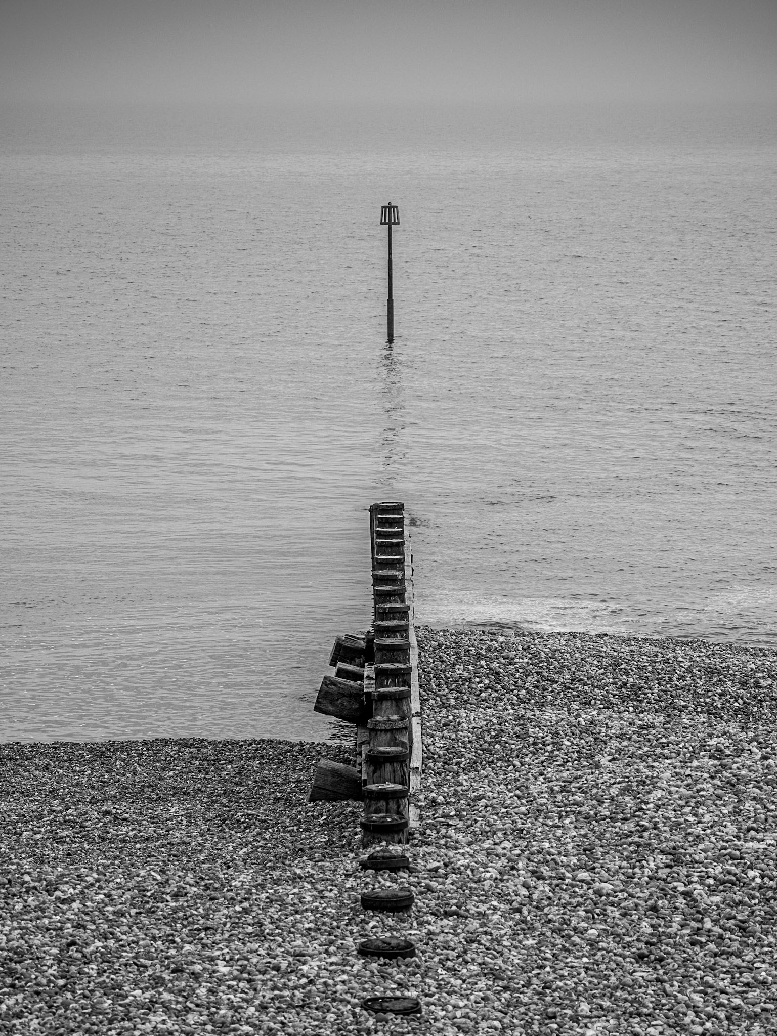 A sole marker stands in the calm seas on a foggy day iin Eastbourne, Sussex