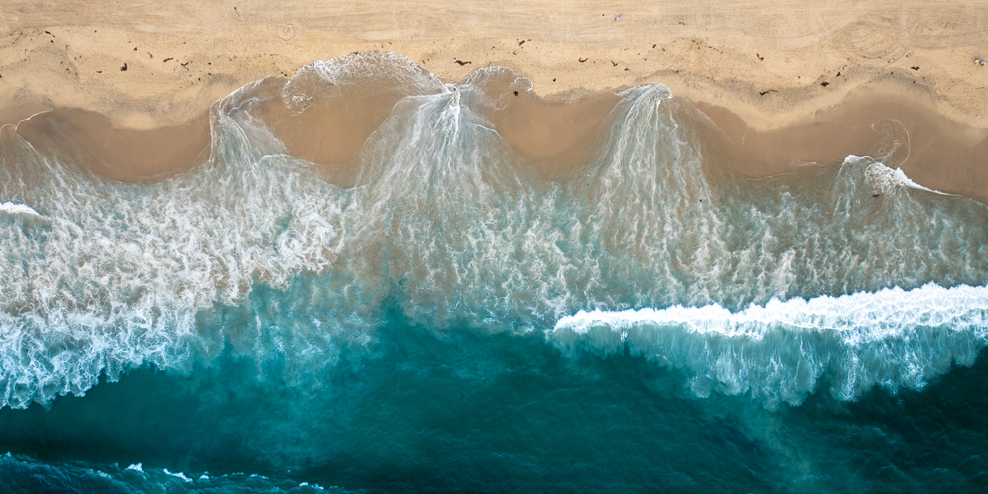 Waves of the Pacific Ocean crash against the golden sands of a beach in one of the surburbs of Los Angeles