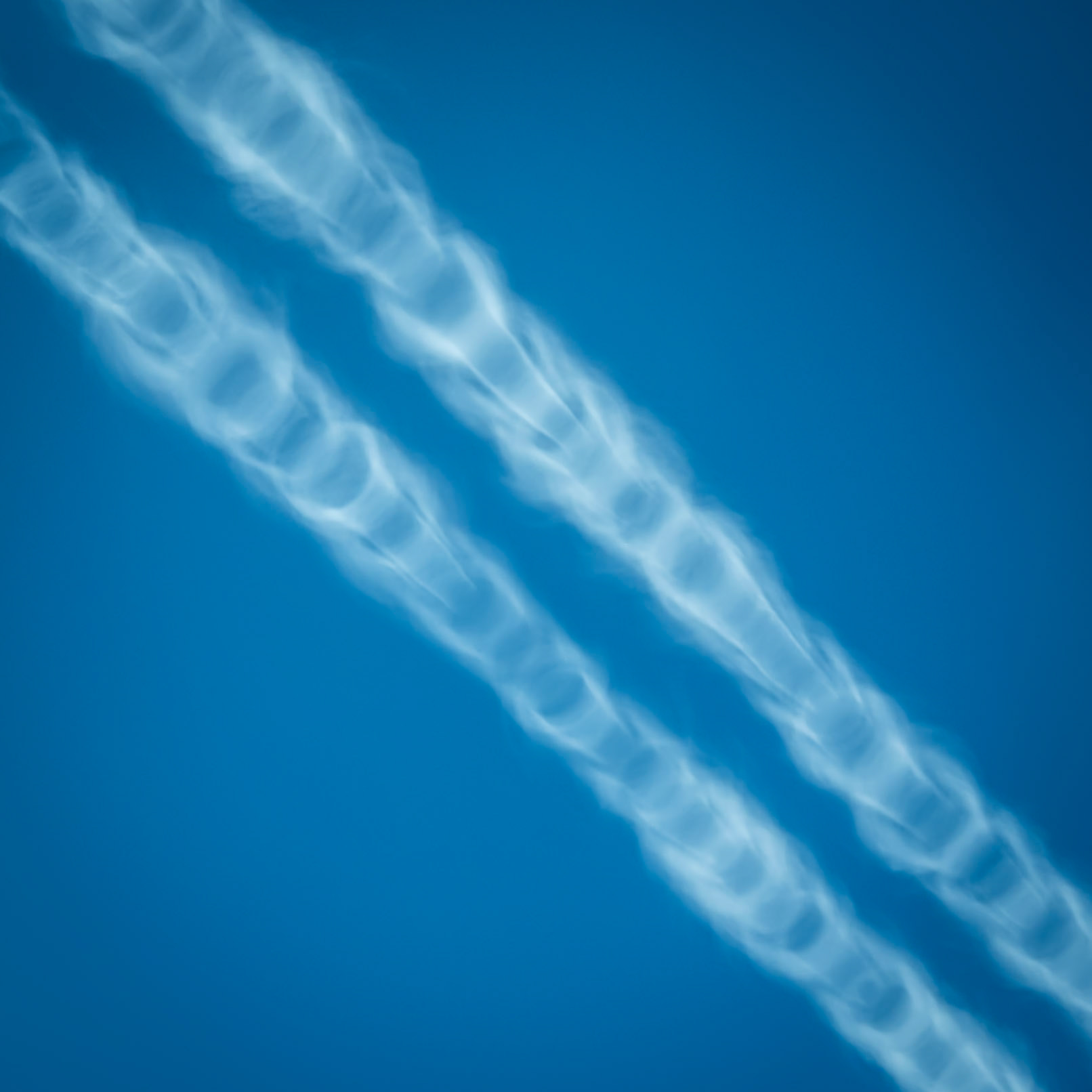 Swirling tunnels of condensed air form stark contrails behind an airliner over the Black Sea