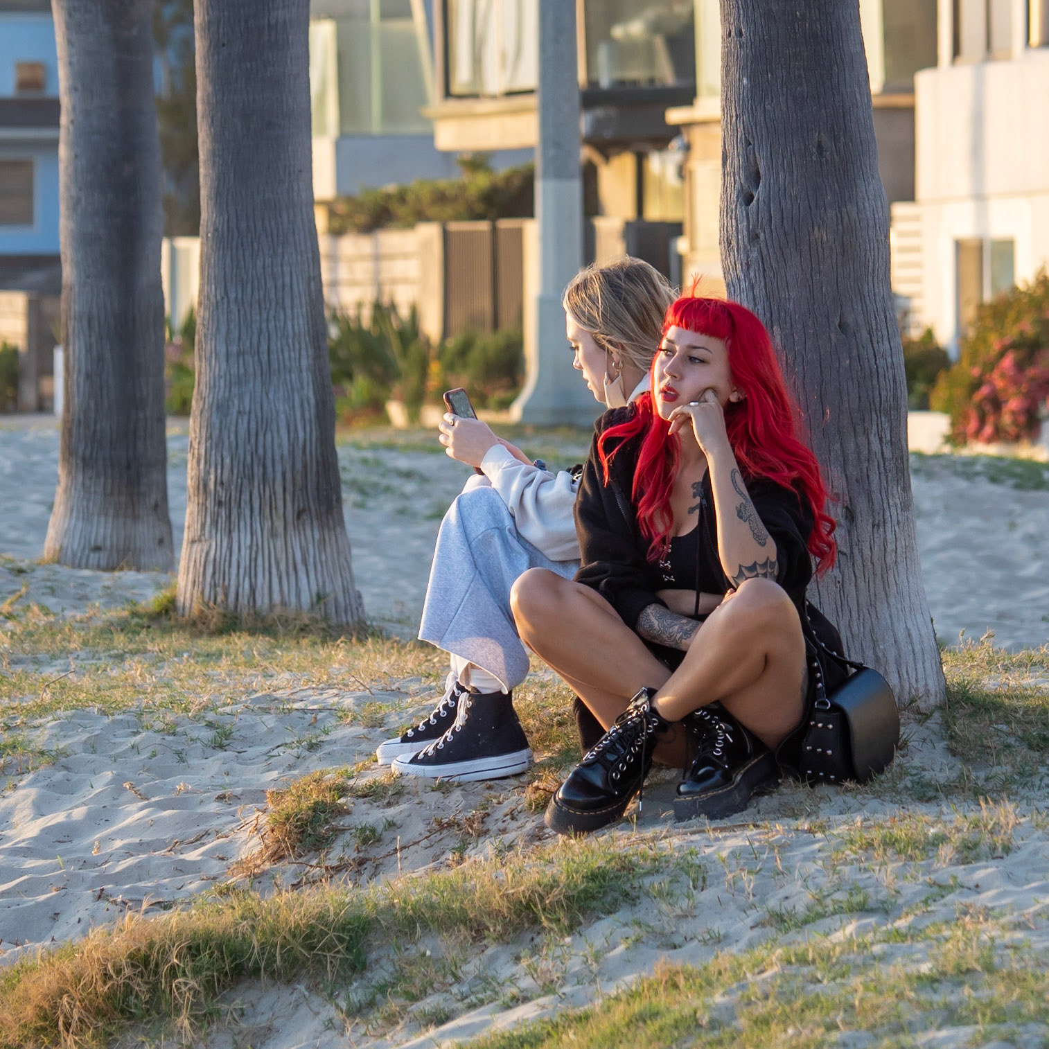 A red-haired girl relaxes with a friend in the sunset on Venice Beach